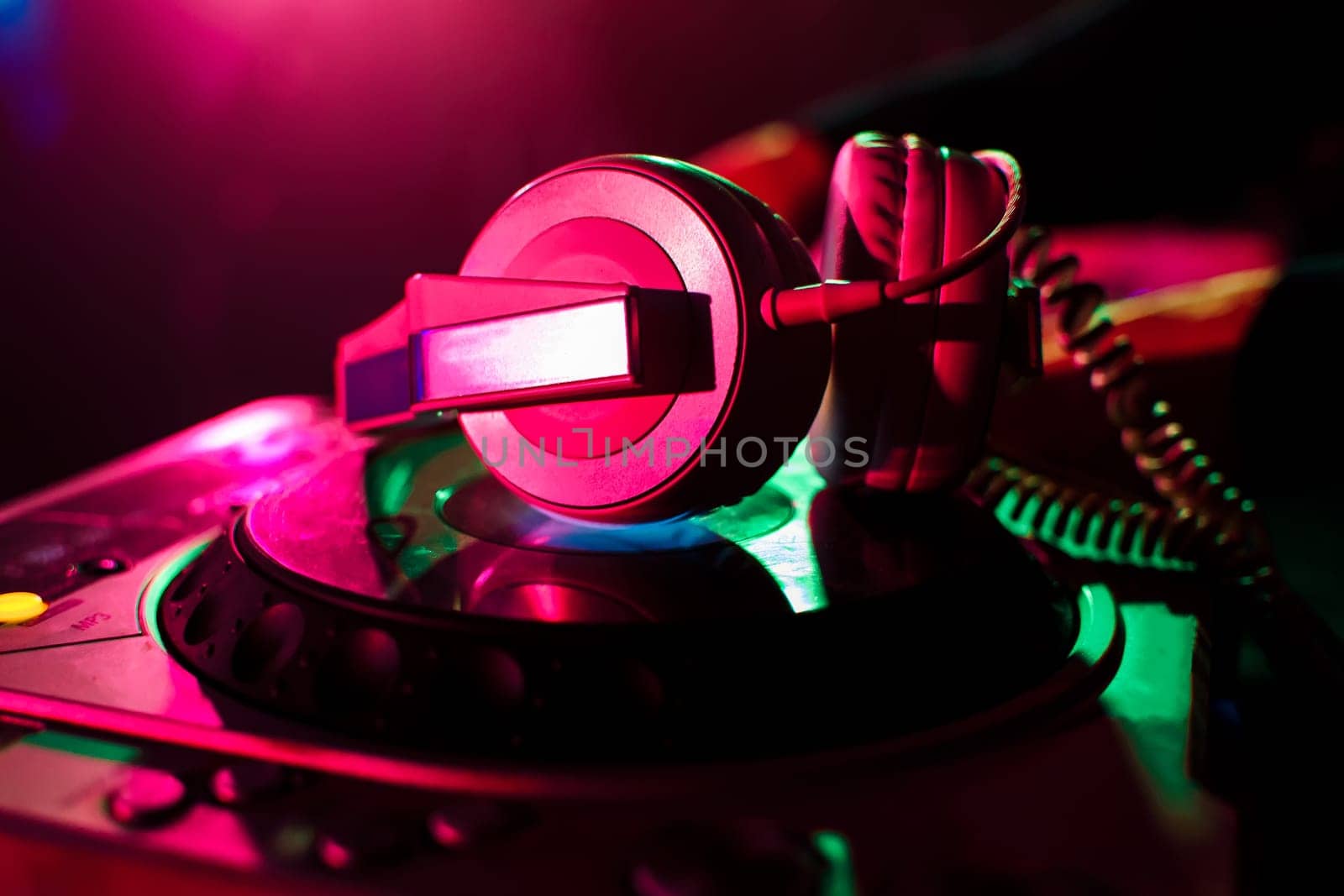 professional headphones and mixer DJ for music in a nightclub on the background color lasers