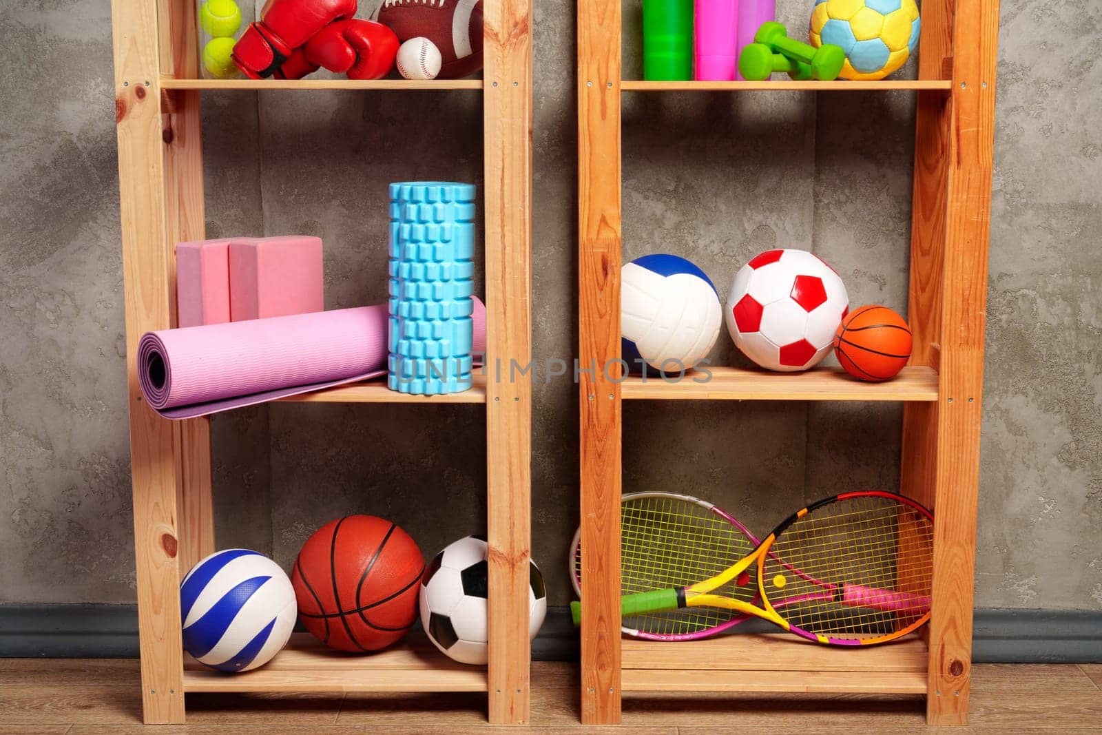 Shelves with different sports equipment against green wall by Fabrikasimf
