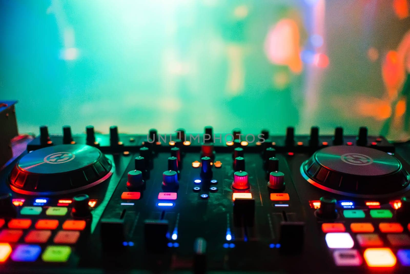 Dj mixer with headphones at nightclub. In the background laser light show