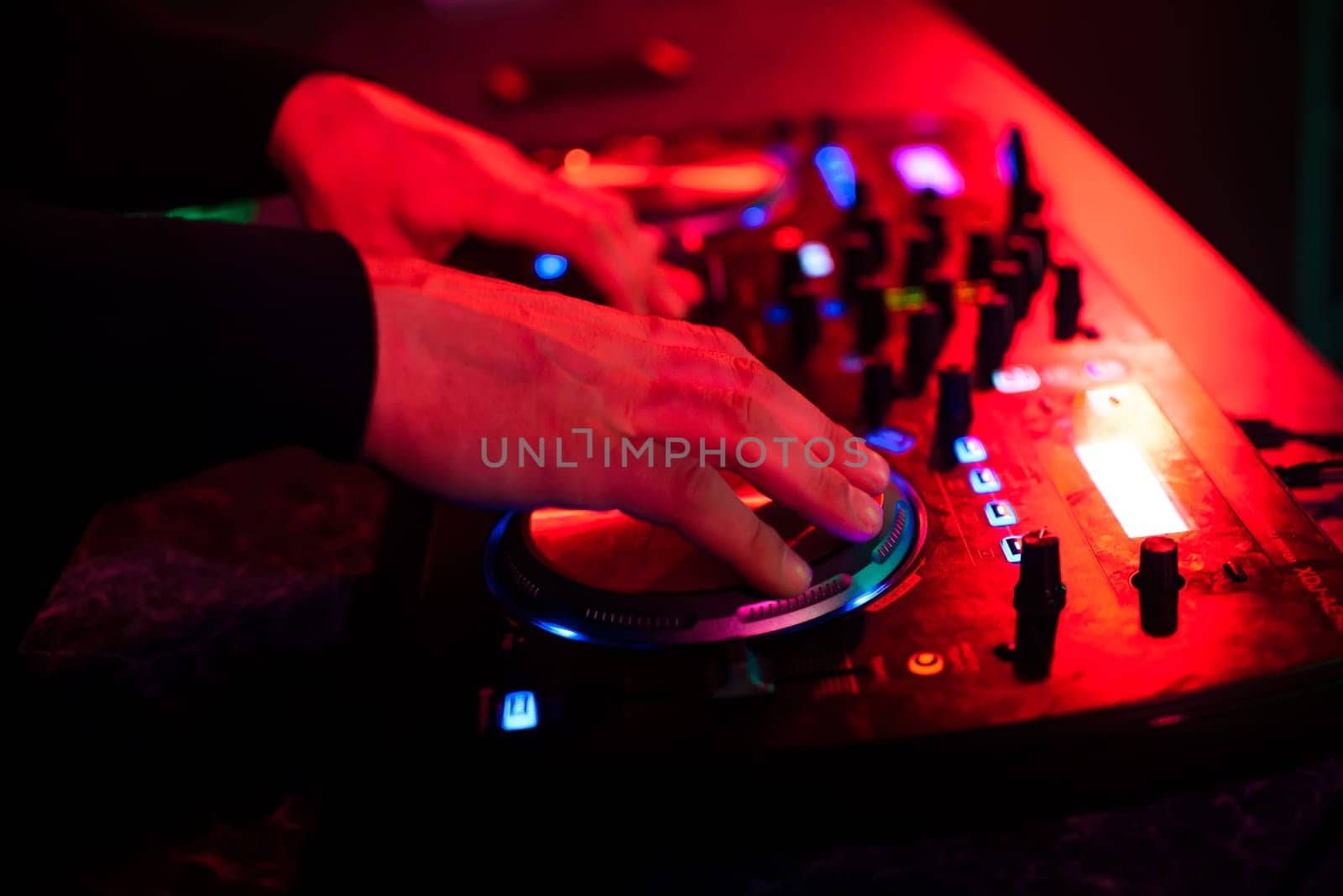 DJ hands mix music on professional mixer in booth at a party in nightclub