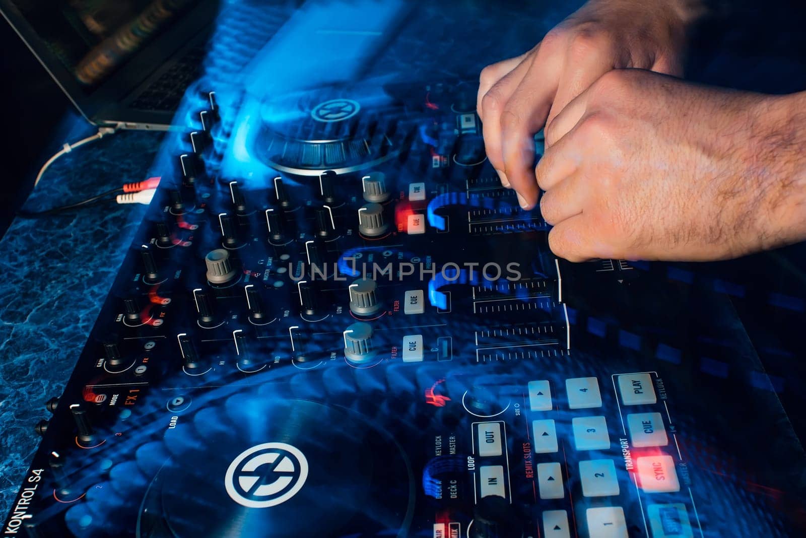 DJ playing music on professional contemporary mixer moving the controllers with blue led light
