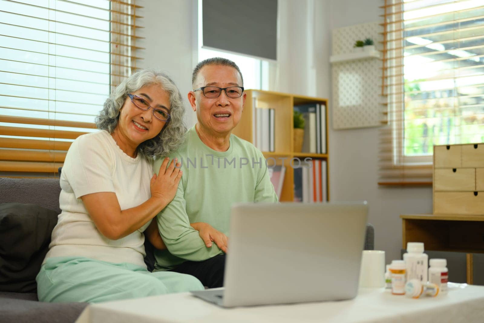 Cheerful senior couple in video conferencing with general practitioner on laptop. Telehealth concept.