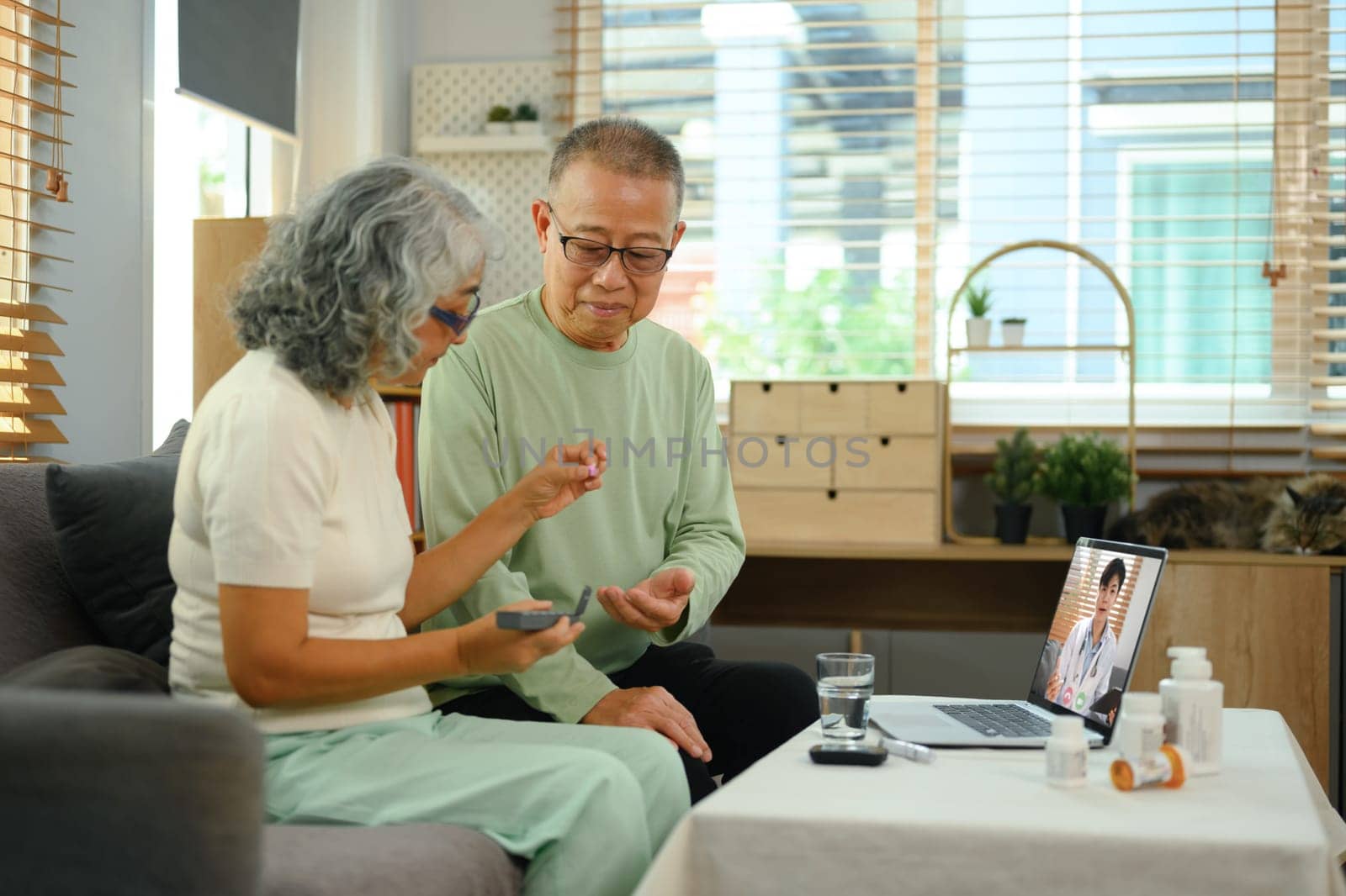 Elderly couple having online medical consultation with general practitioner via laptop. Telehealth concept.