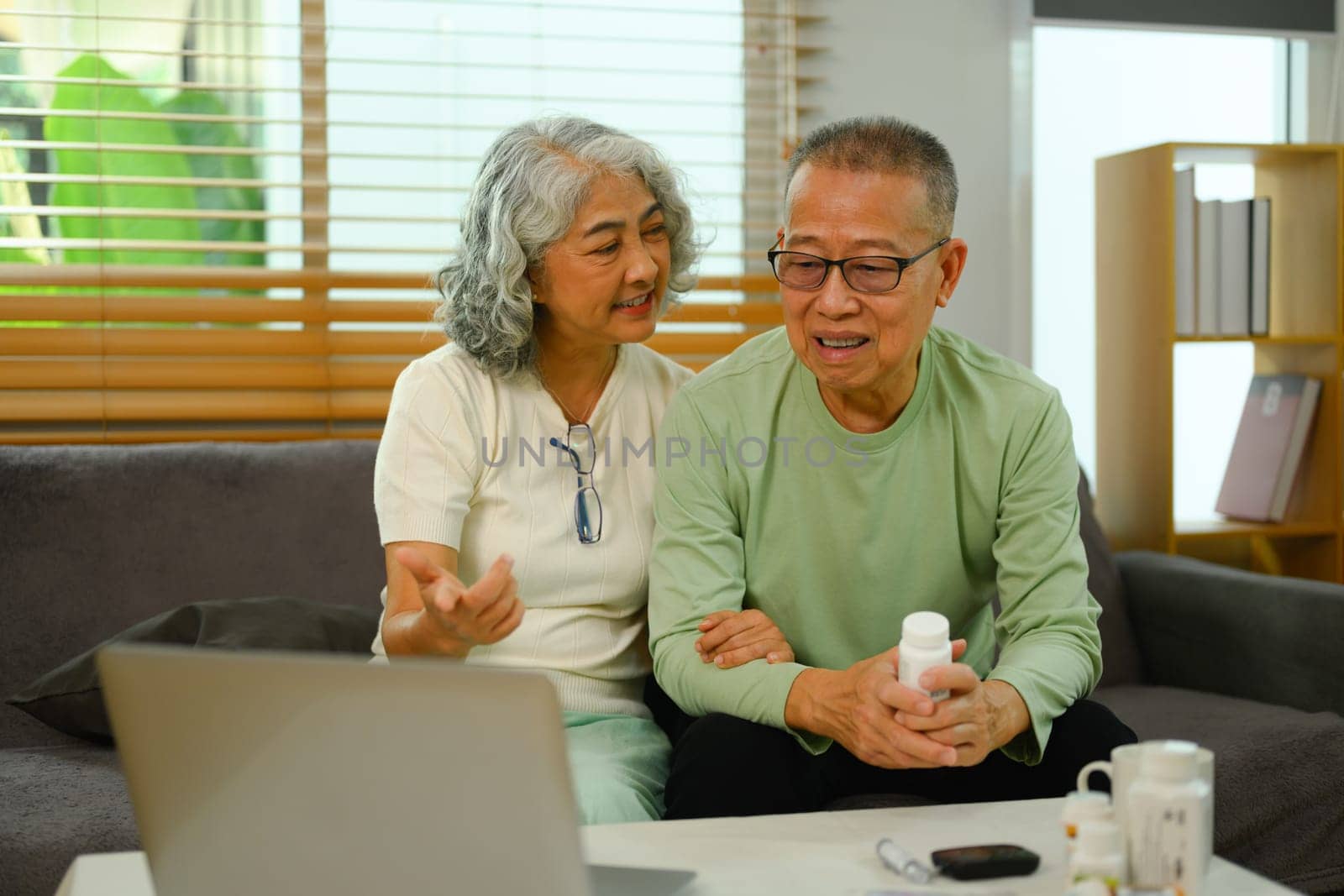 Mature couple making video call with their doctor on laptop at home. Telehealth concept.