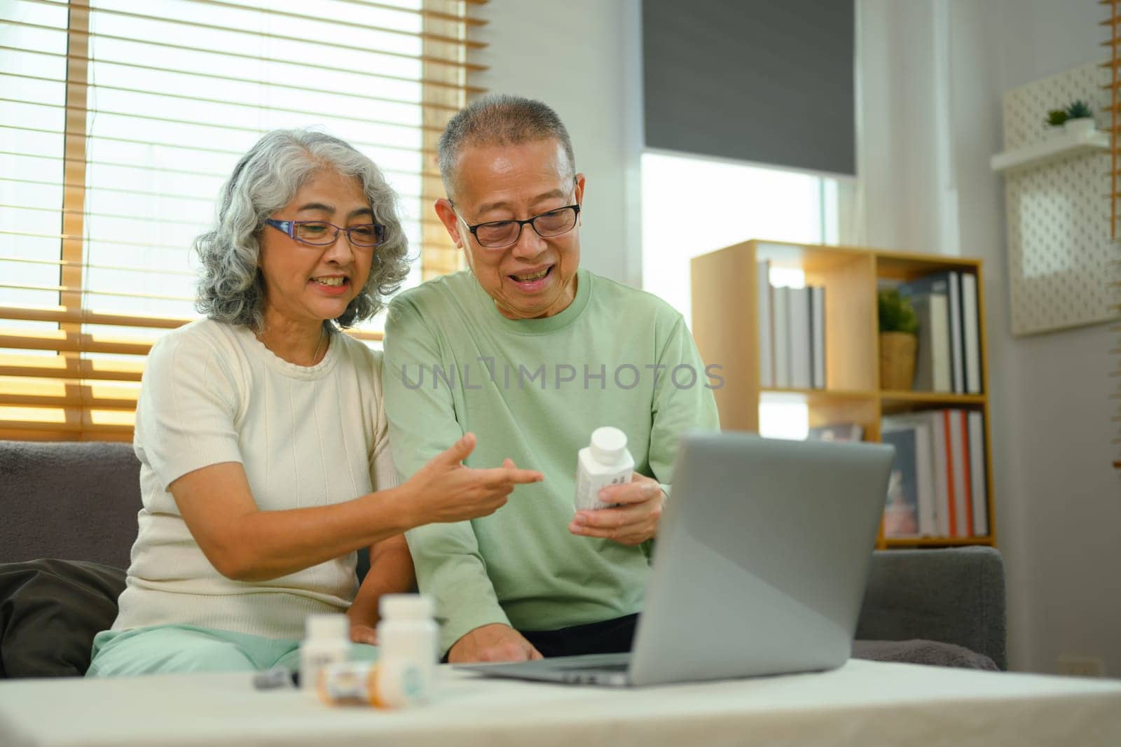 Smiling elderly couple in video conferencing with general practitioner on laptop. Telehealth concept.