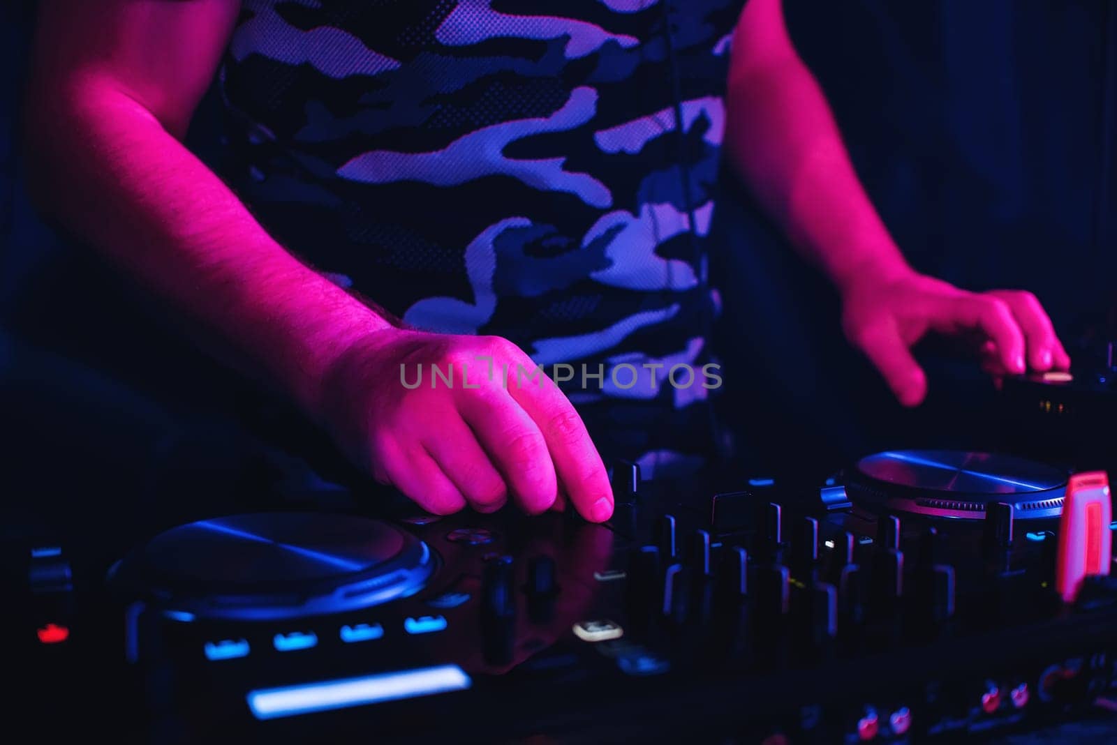 DJ playing in nightclub on the mixer and a professional equipment for color spotlight