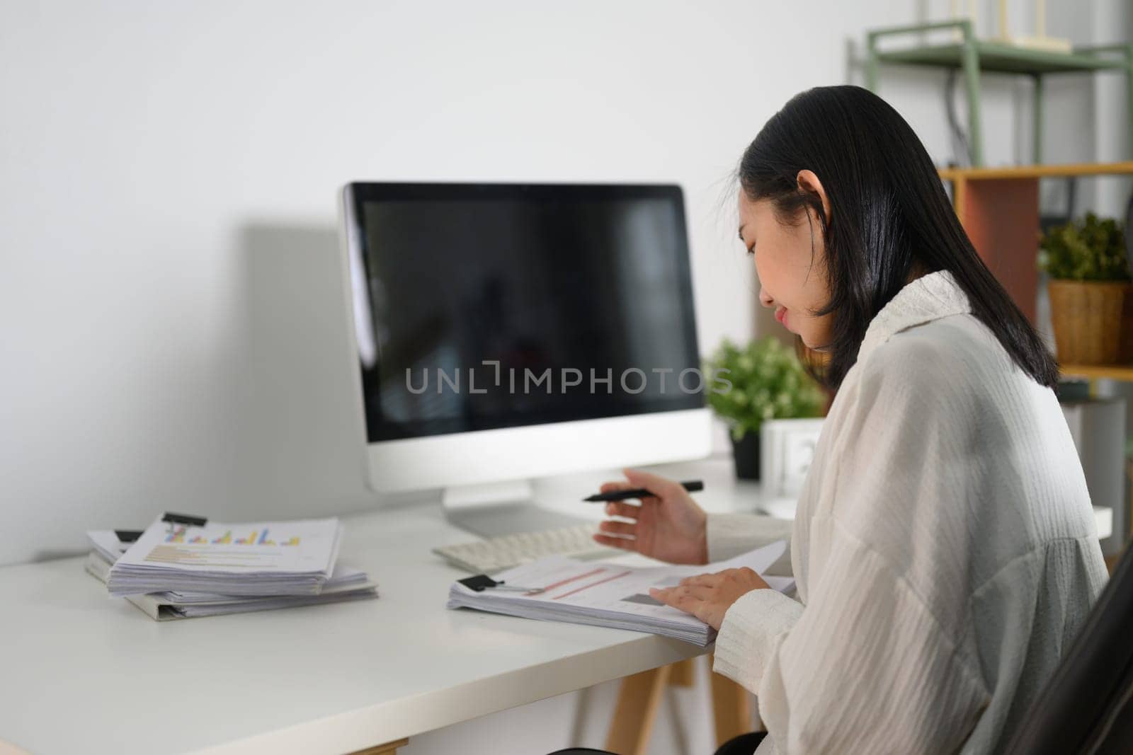 Focused businesswoman analyzing financial report at her workplace by prathanchorruangsak