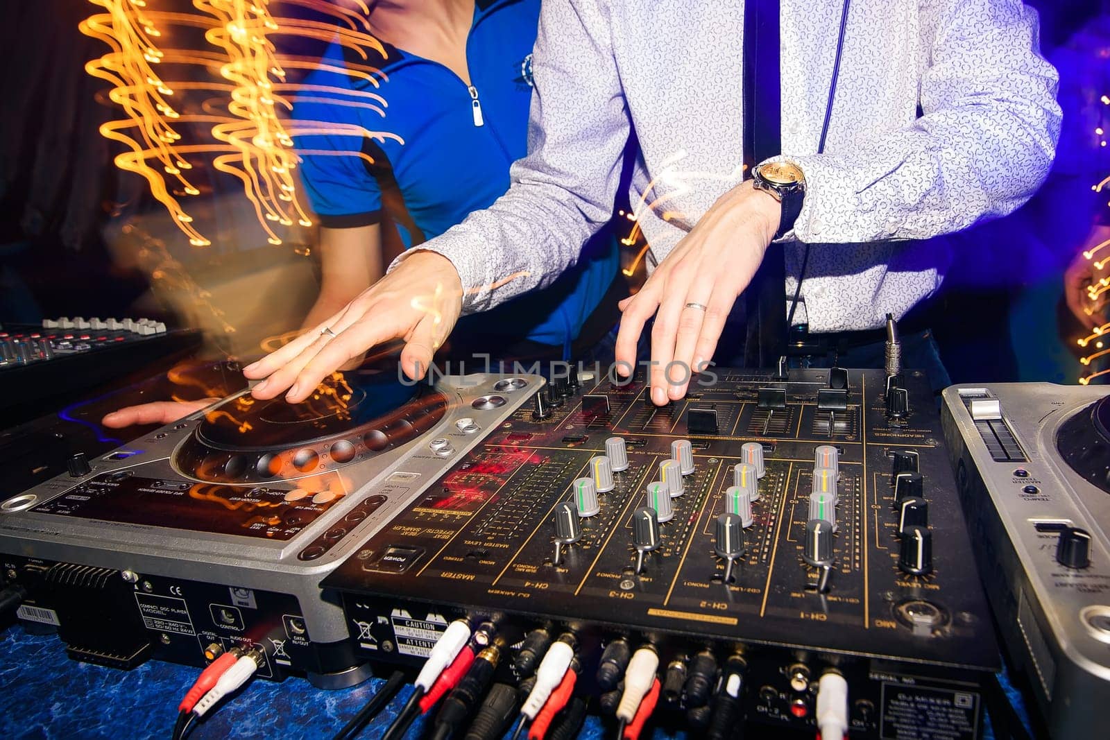 DJ hands mix music on professional mixer in booth at a party in nightclub