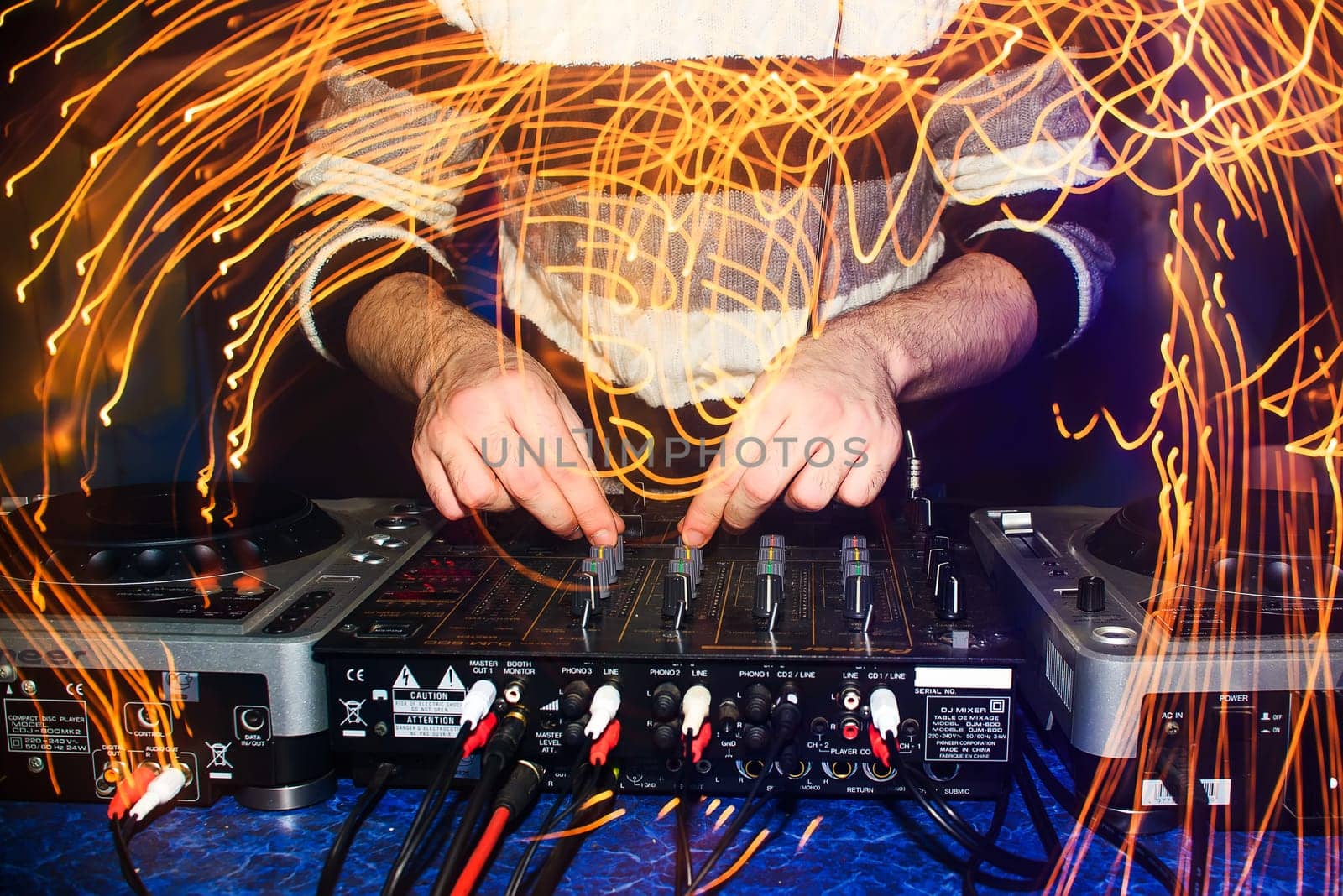 DJ hands mix music on professional mixer in booth at a party in nightclub