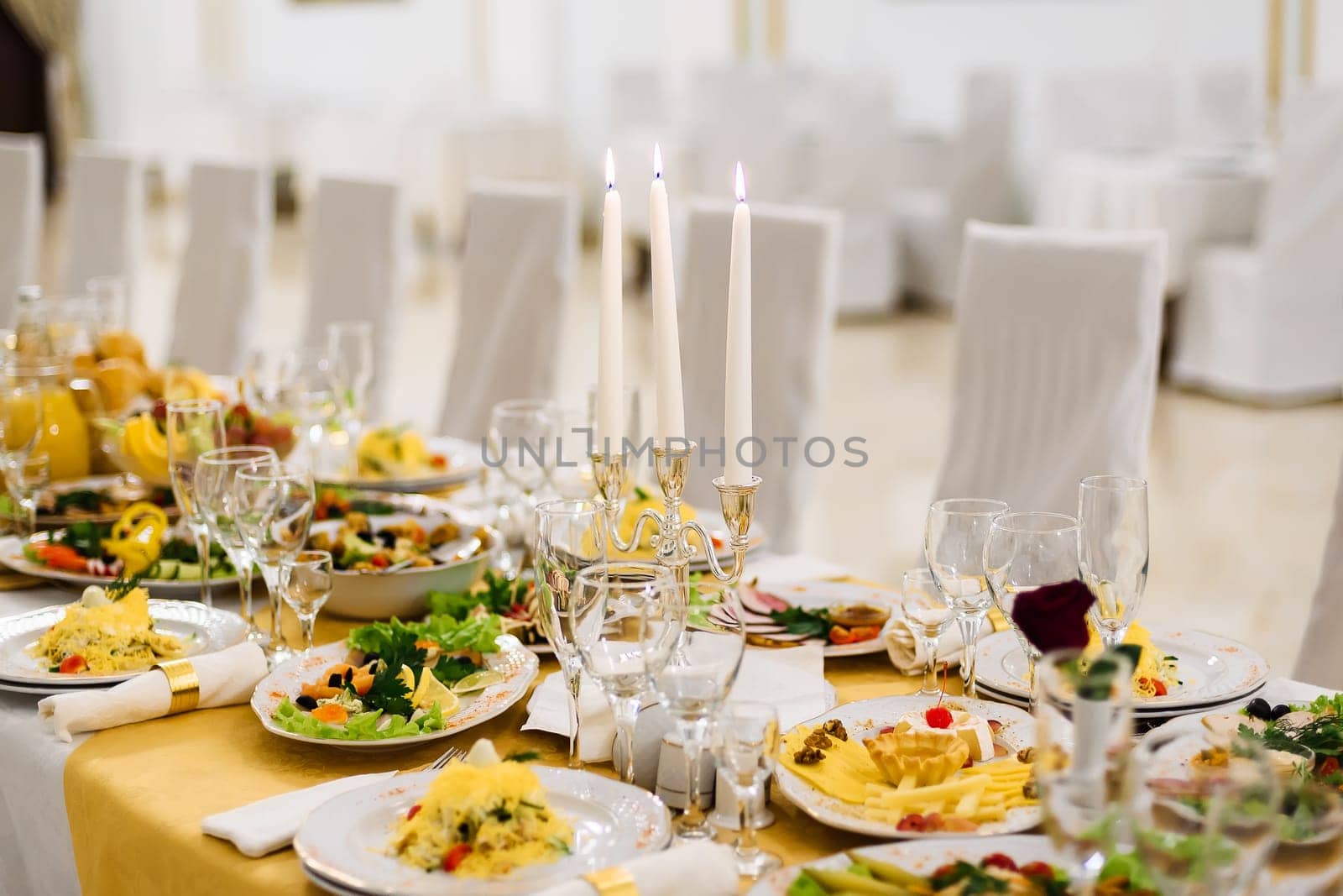 table covered with food and dishes with glasses on a tablecloth in a restaurant for holiday
