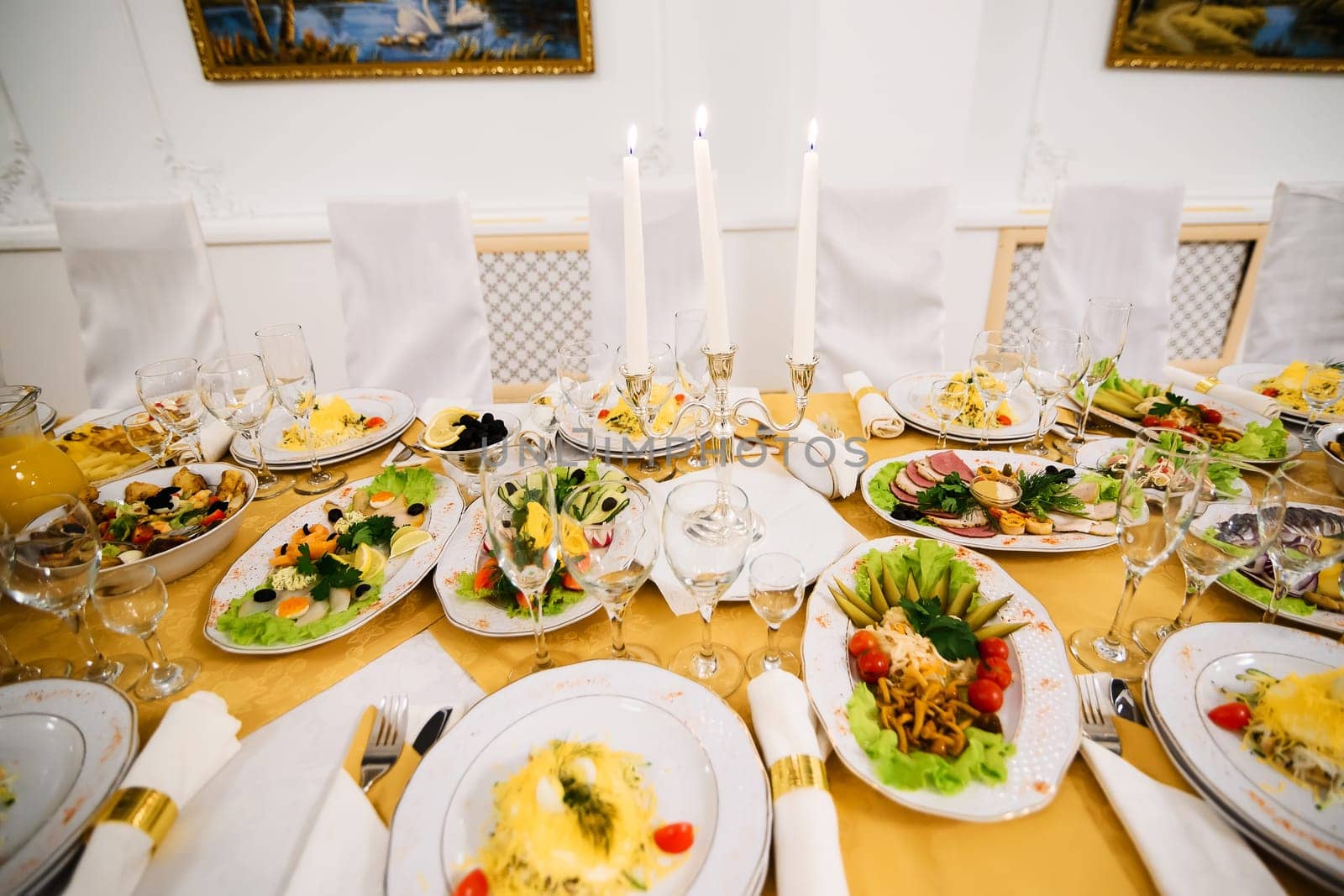 table covered with food and dishes with glasses on a tablecloth in a restaurant for holiday