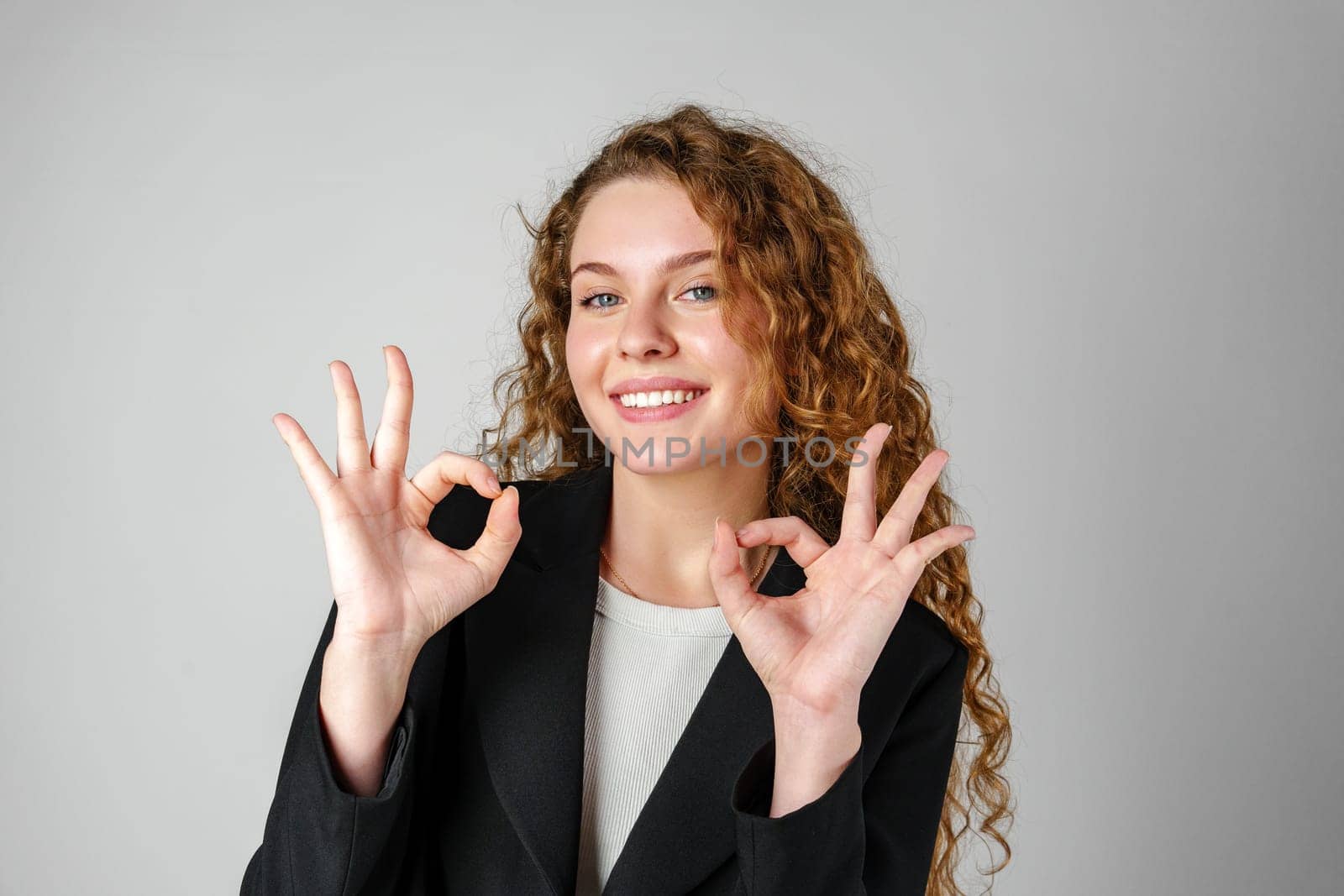 Young Woman Giving Ok Sign on gray background close up