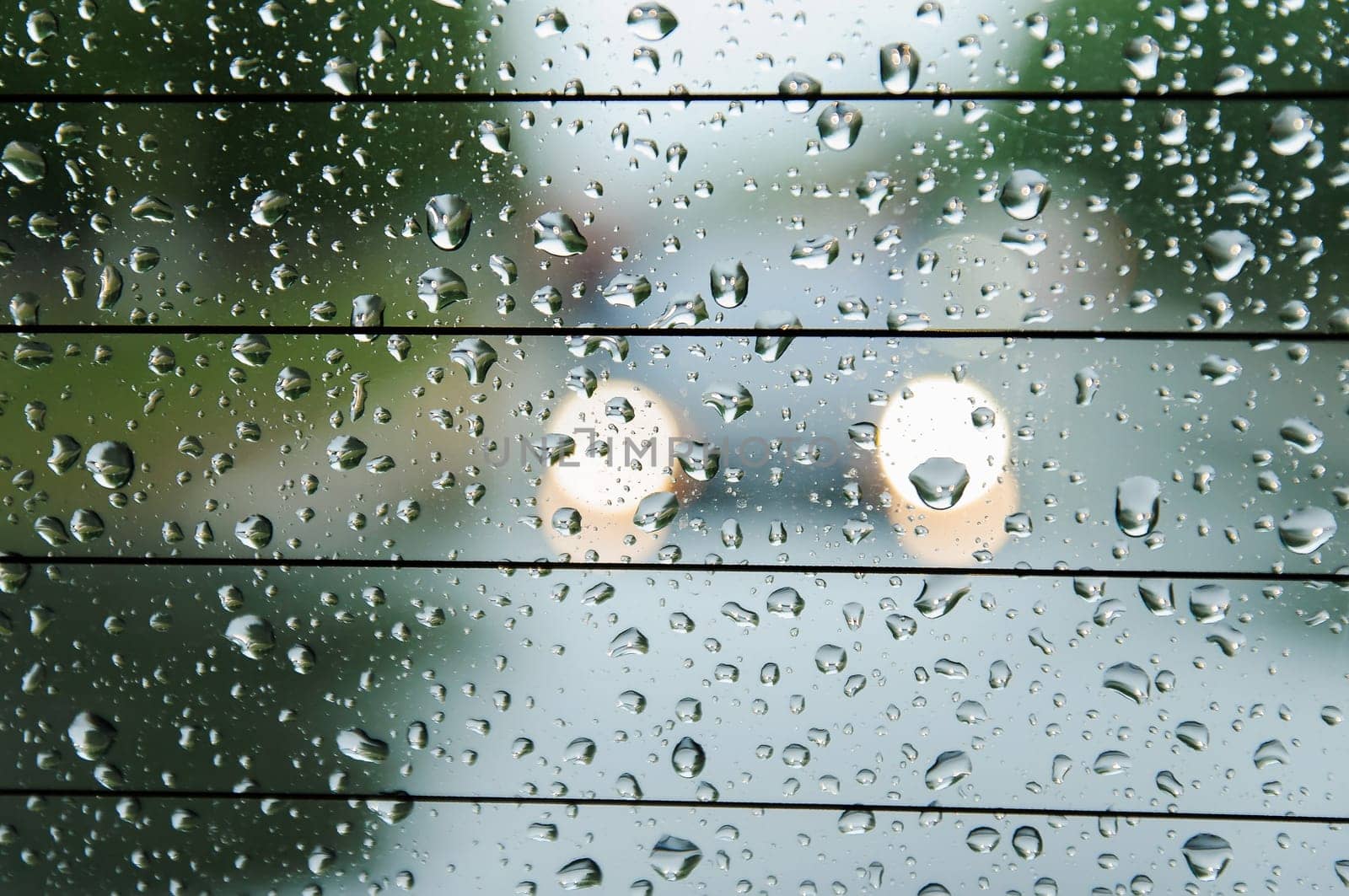 raindrops on the surface of the car glass in rainy weather with a blurred background on the street