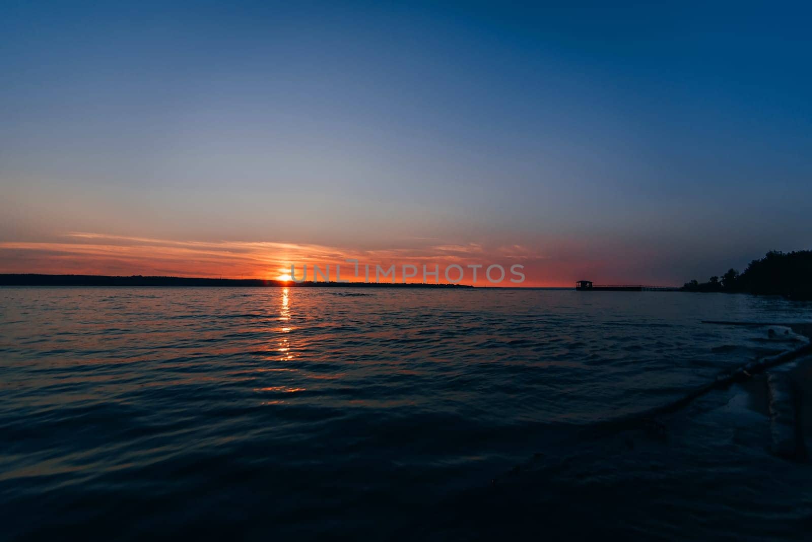 beautiful sunset on the river with the outgoing red sun and the blue sky