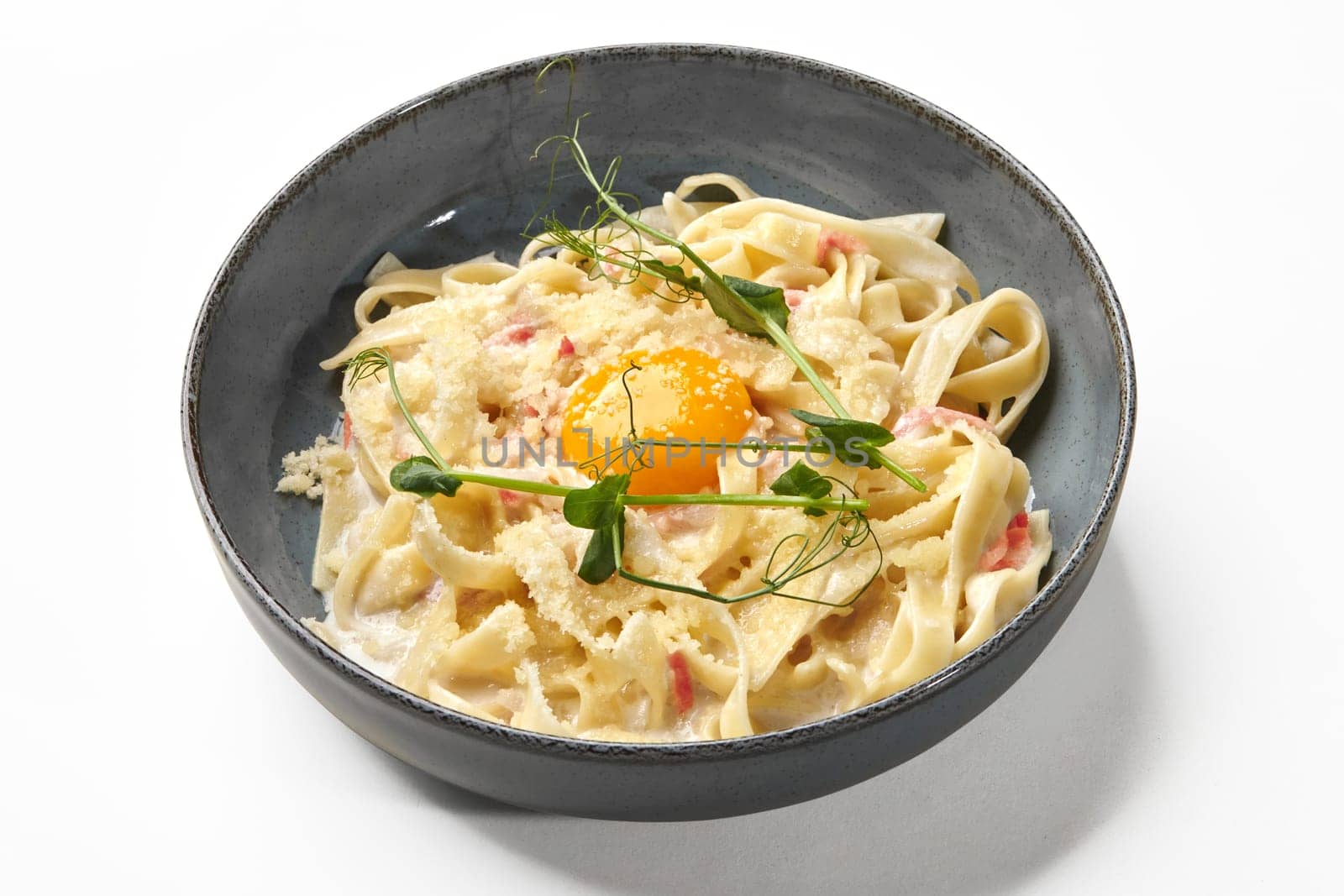 Creamy fettuccine carbonara with pancetta and egg yolk on white by nazarovsergey