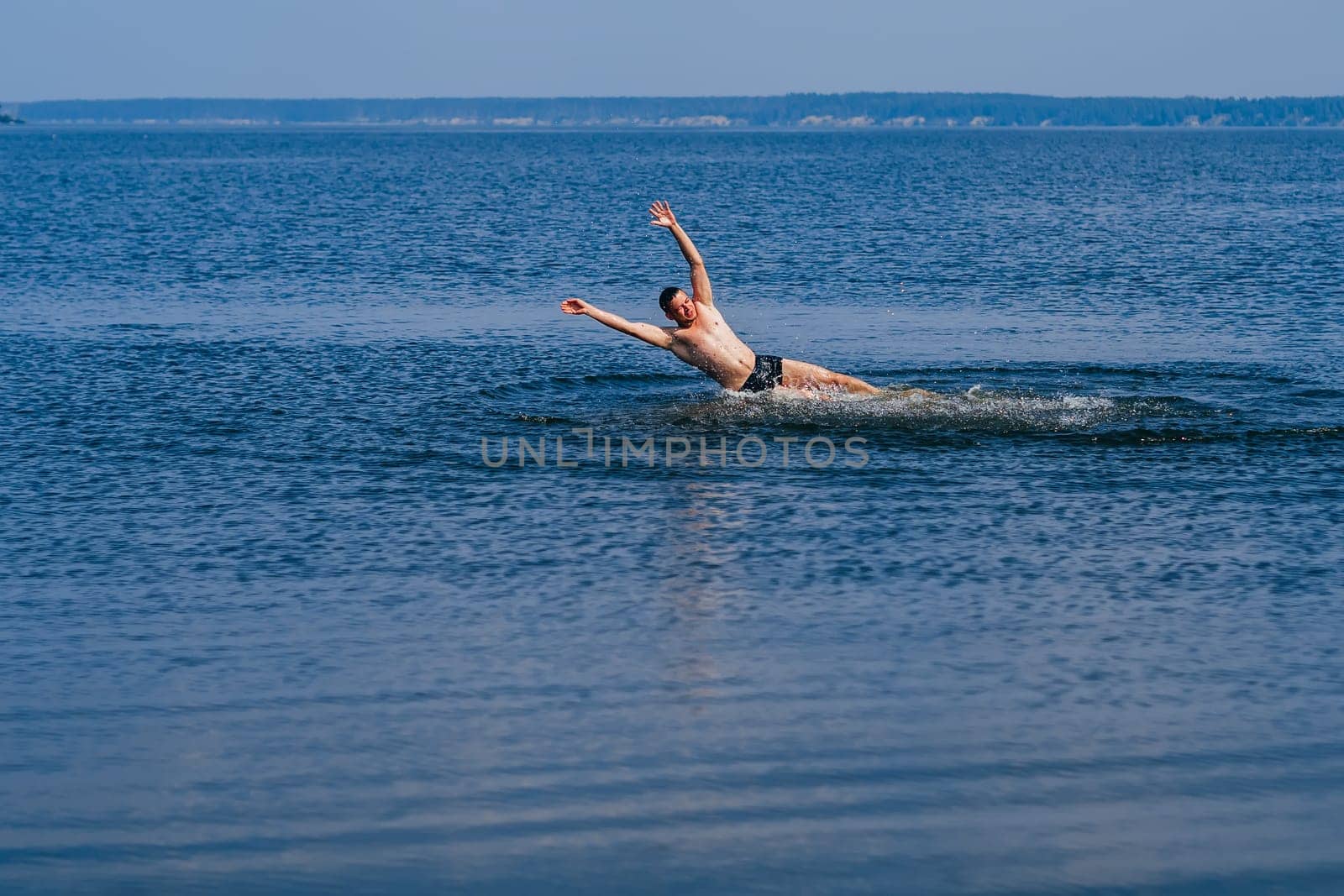 man swims and having fun resting in the water with the spray in summer on the beach