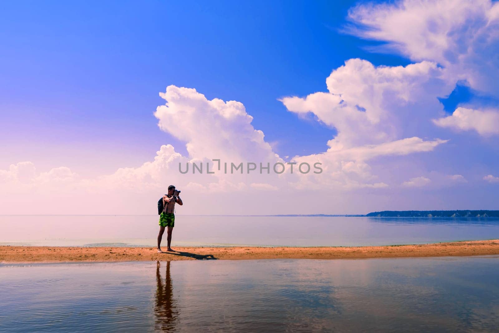 traveler photographer a European with a backpack taking pictures of the water in the summer