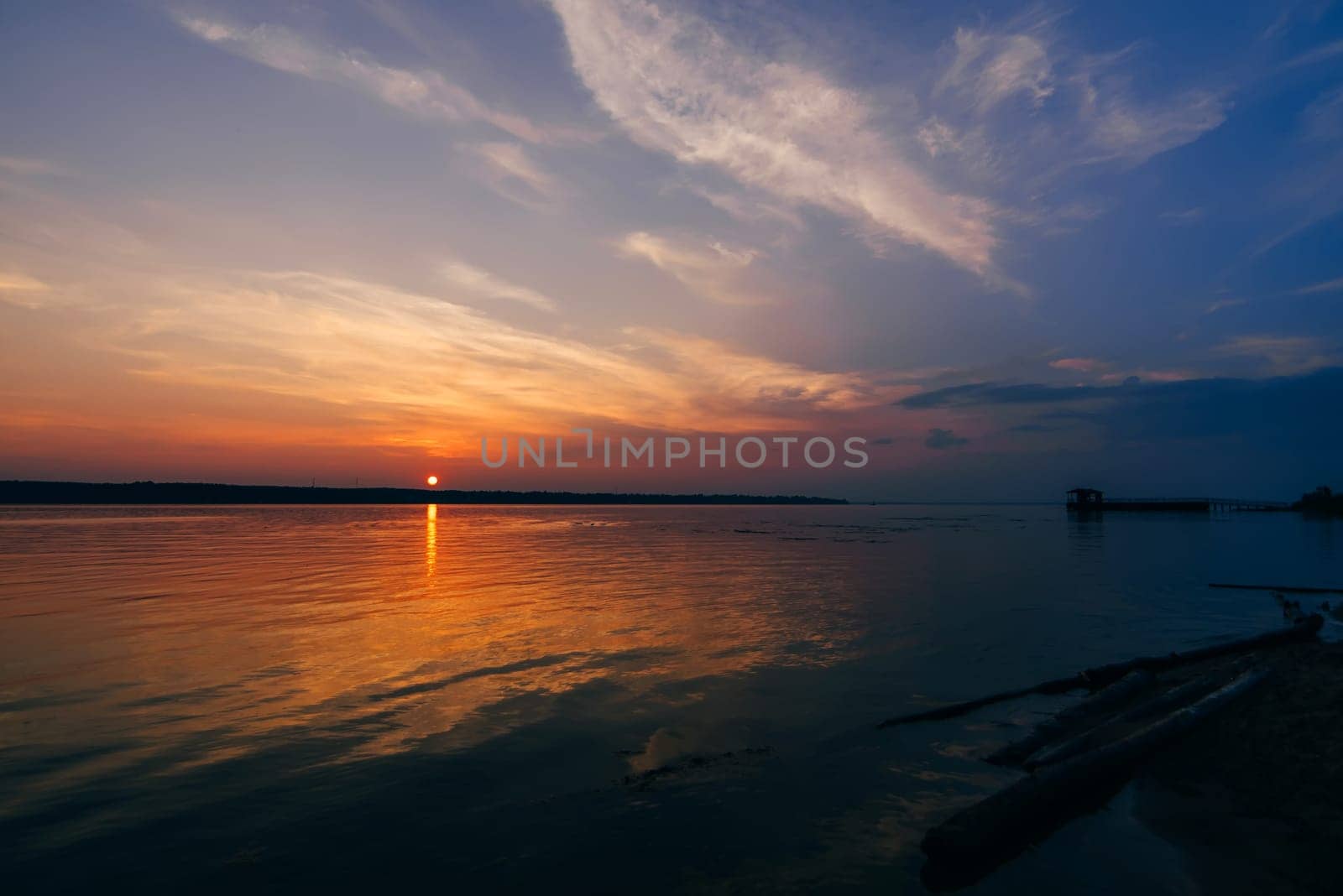 sunset over the river and a beautiful sky on a summer evening and the silhouette of the pier