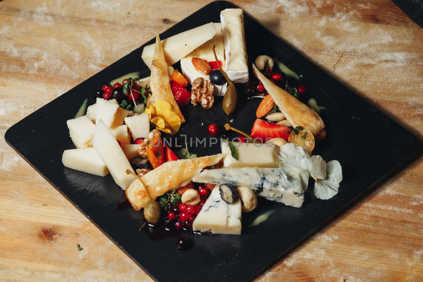 A rustic wooden table displaying a lavish assortment of various cheeses and nuts, creating a delightful feast for the senses.
