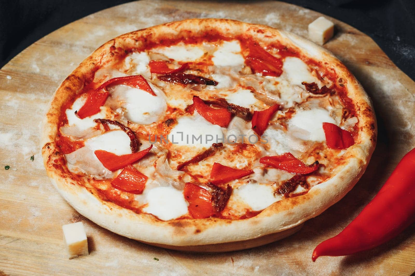 A freshly baked pizza topped with vibrant peppers and gooey cheese rests on a wooden cutting board.