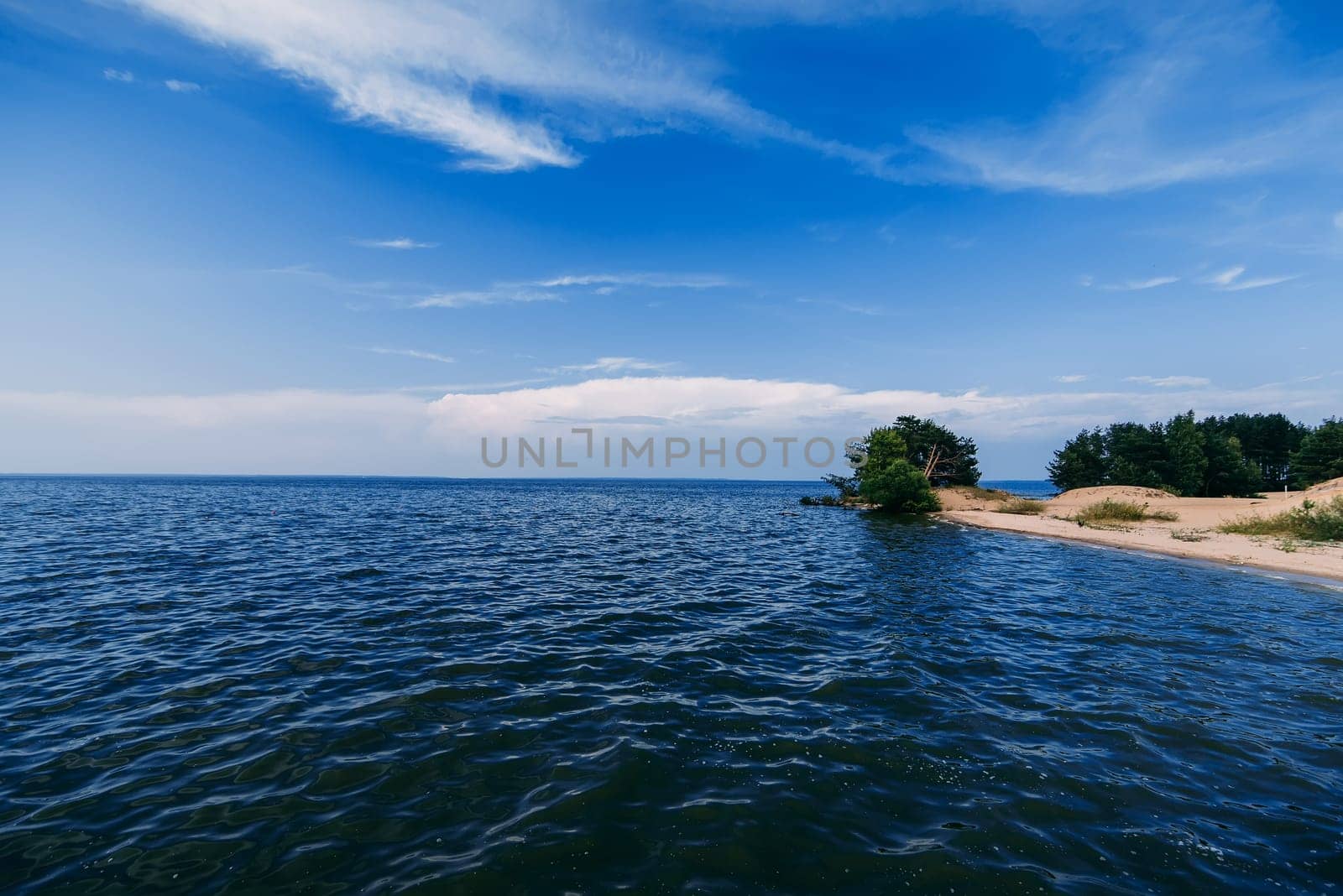 blue clear sky with waves on the water of the sea and a sandy beach on a summer day