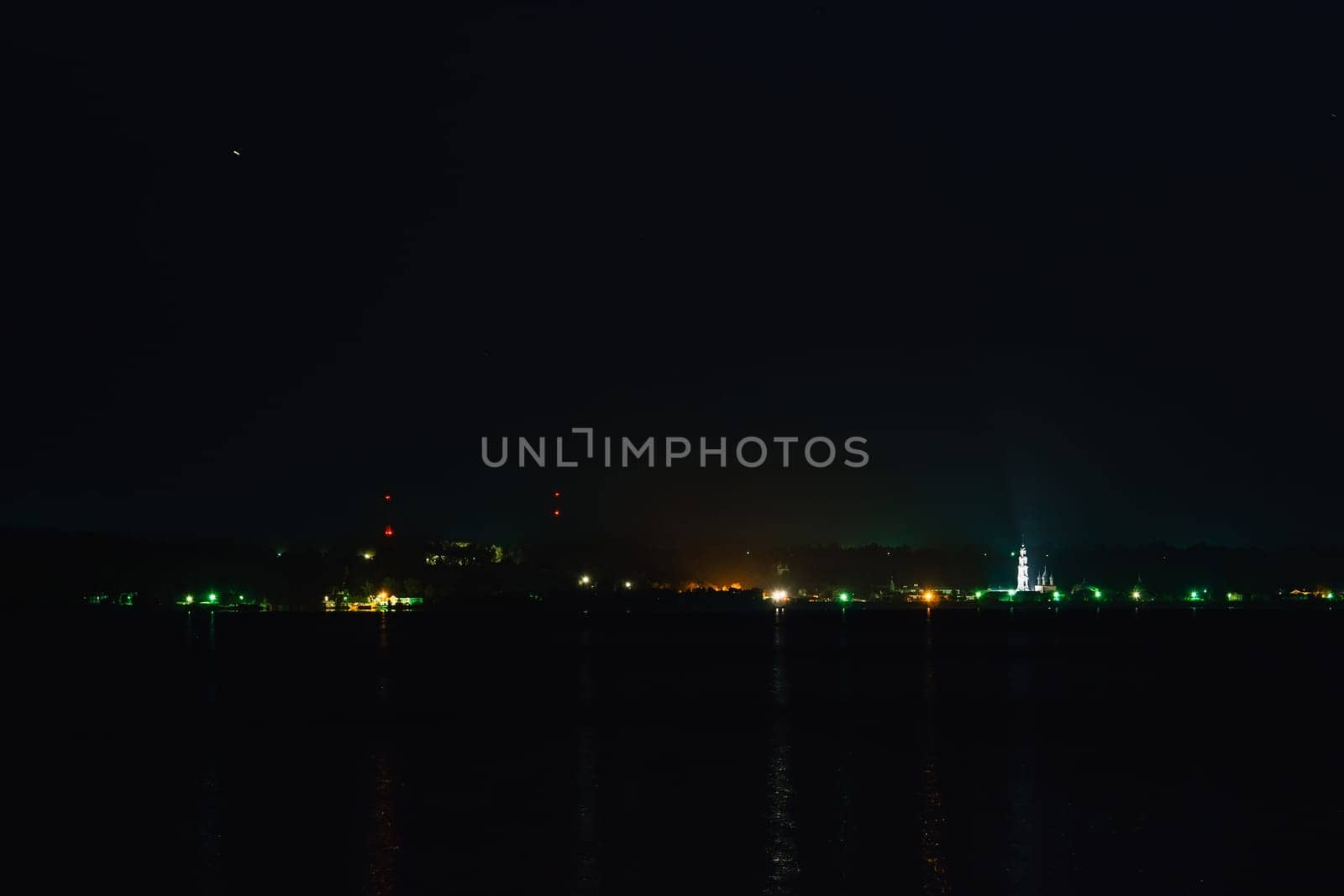 small town lights on the river with reflection in water on a dark night