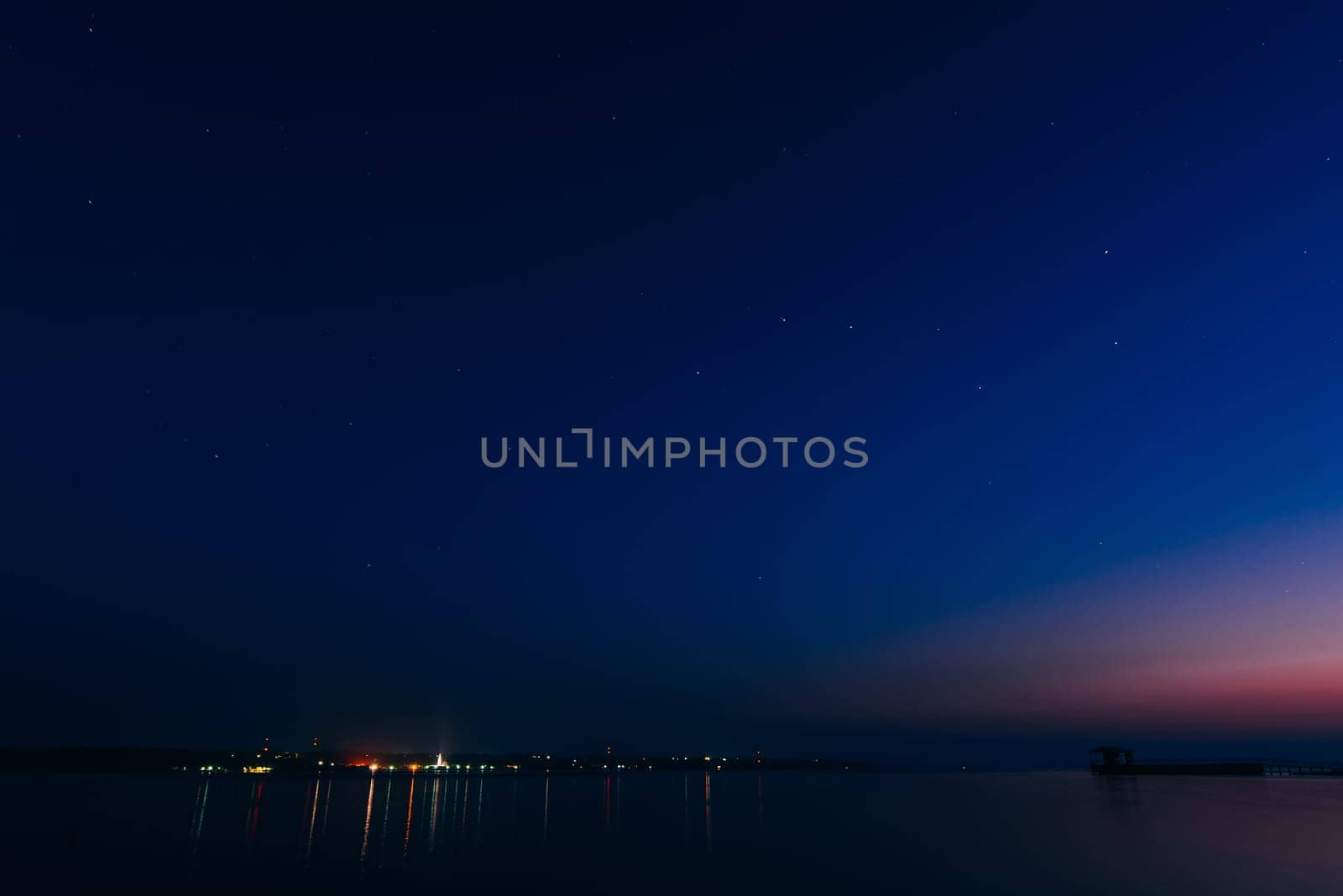 starry night sky with stars and the glowing city on the banks of the river