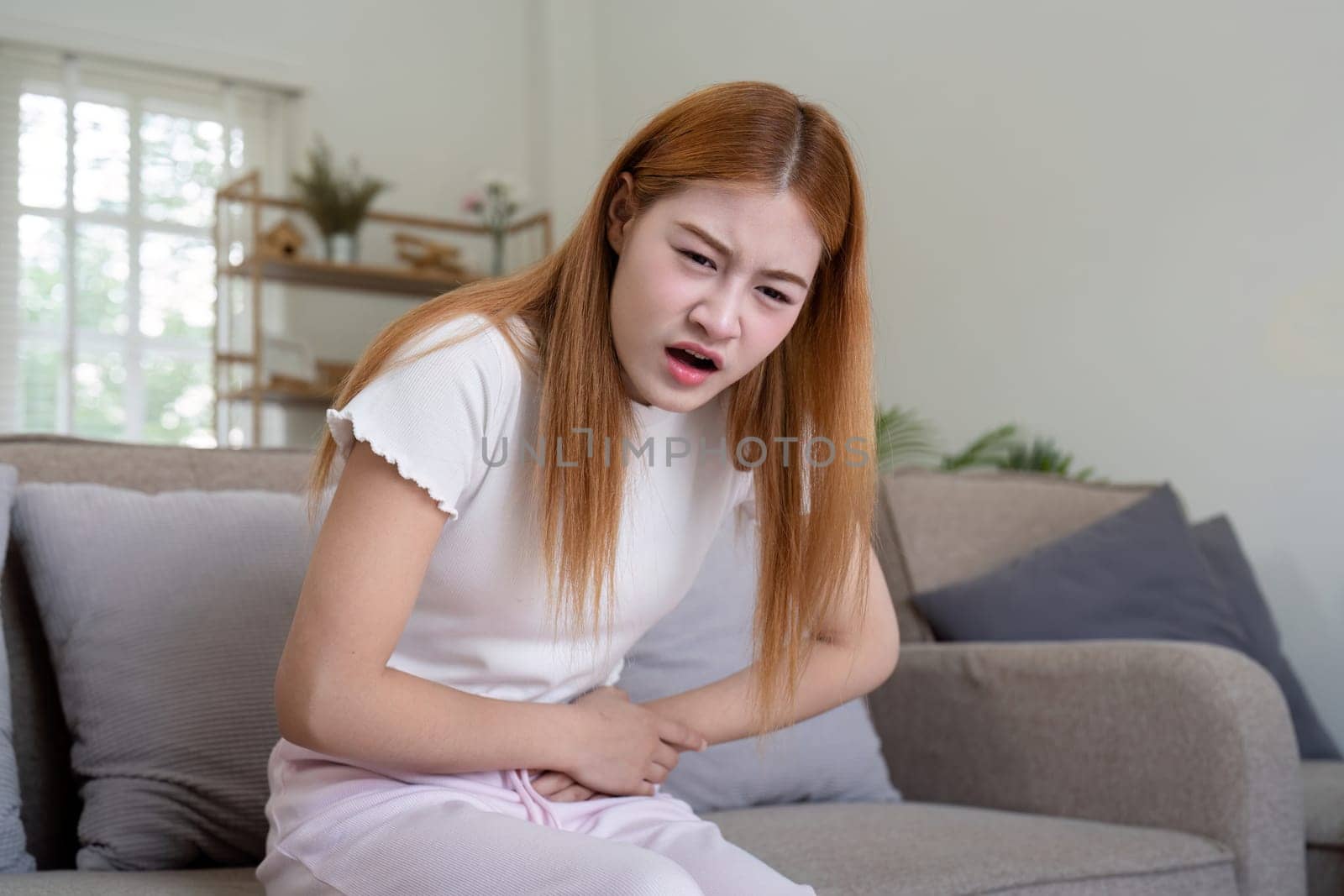 Asian woman having painful from stomach ache at home, Female suffering with abdominal pain by nateemee