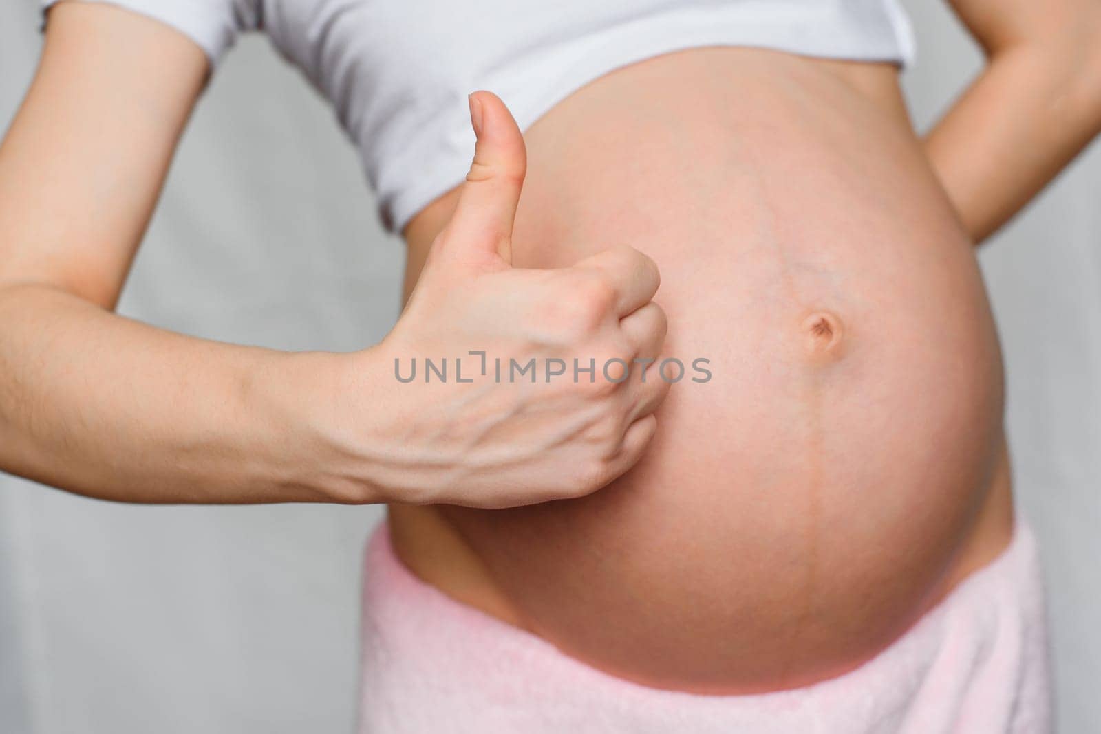 pregnant girl makes a gesture class is a hands on background belly