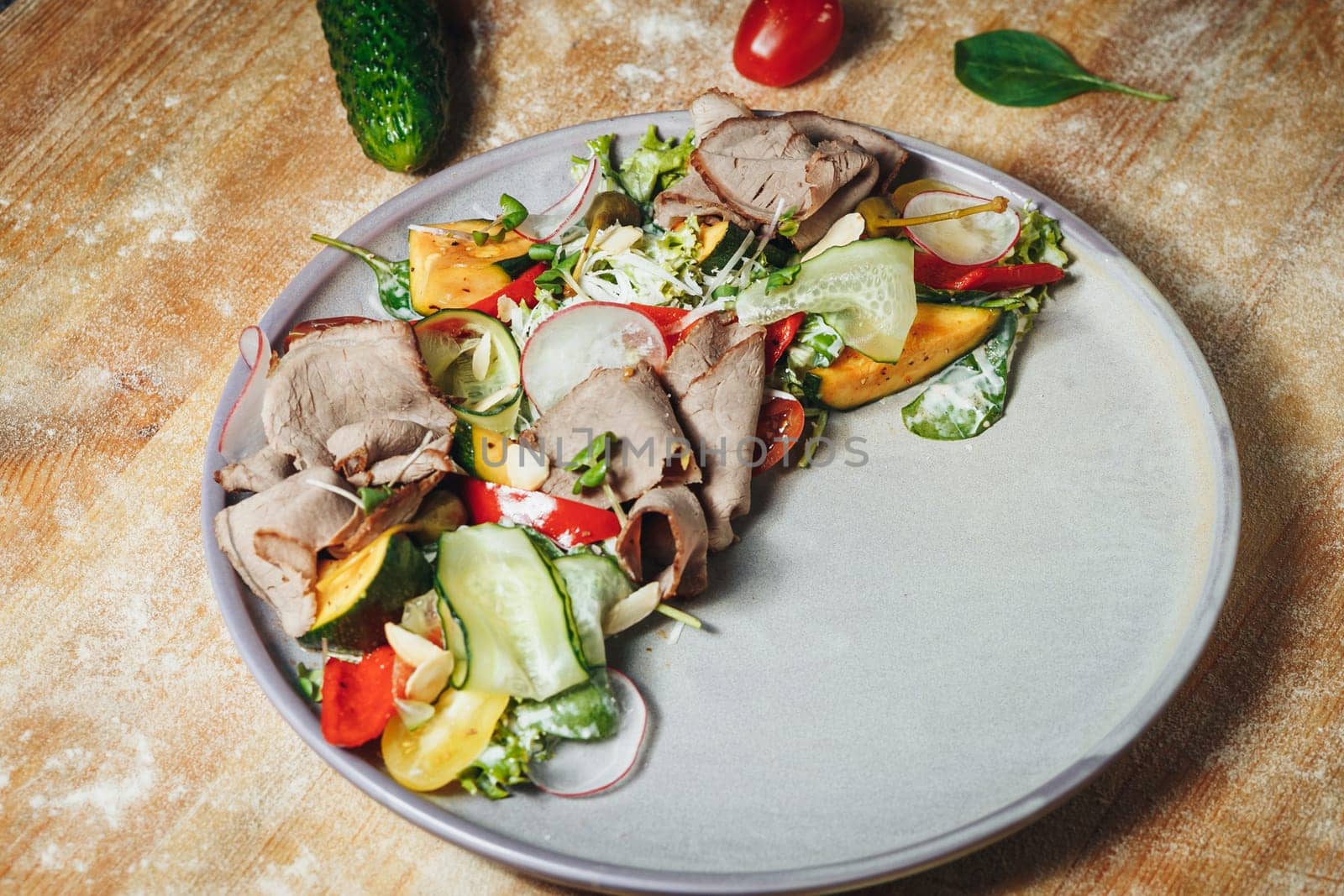 A colorful assortment of fresh vegetables and savory meats arranged on a natural wooden table, showcasing a healthy and delicious meal.