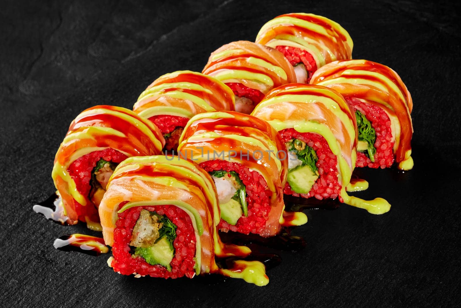 Colorful red rice uramaki rolls with shrimp tempura, salmon and sauces by nazarovsergey