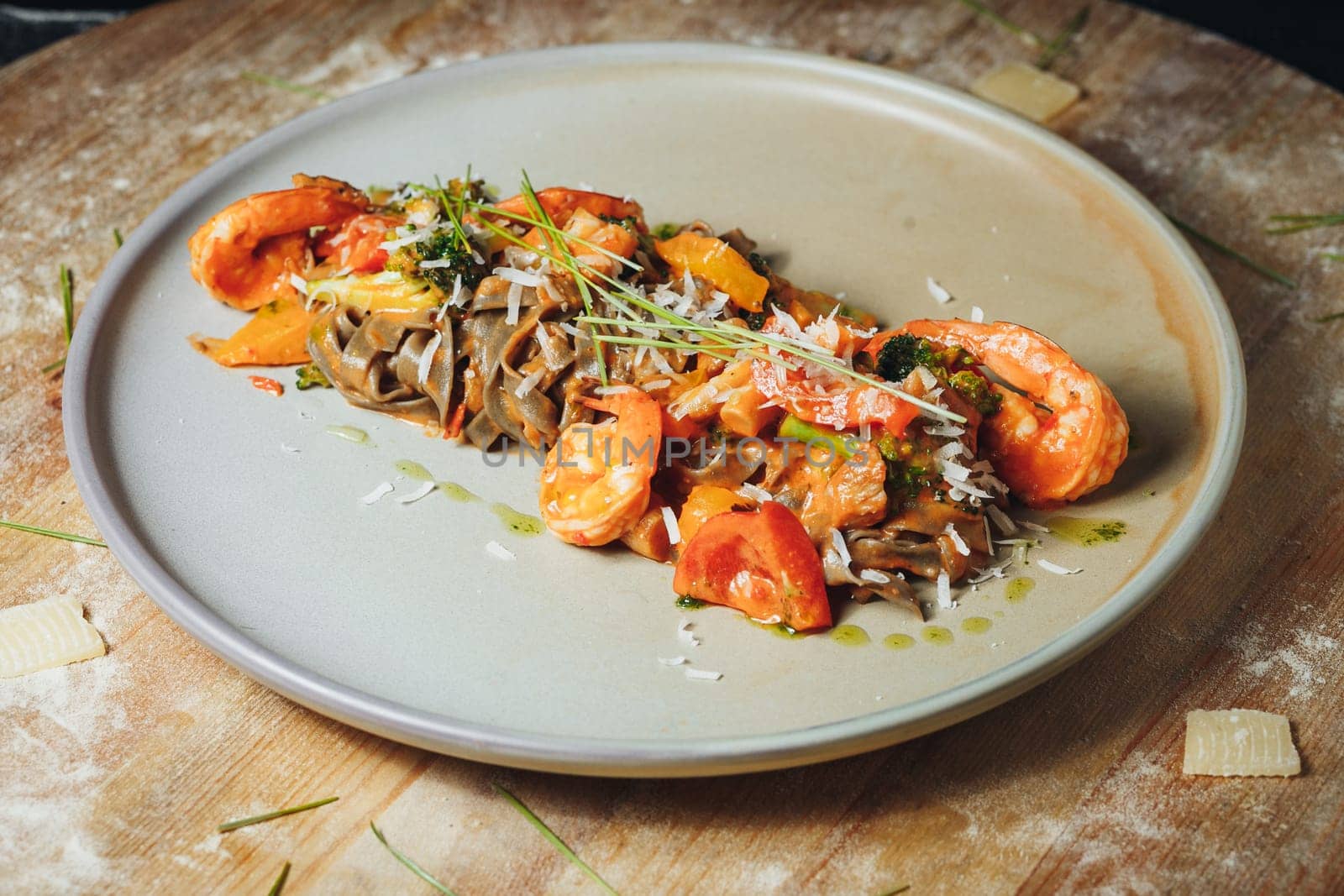 A delicious plate of pasta topped with succulent shrimp and fresh tomatoes, ready to be savored.