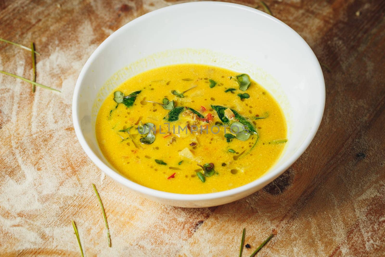 A bowl of creamy pumpkin soup garnished with herbs and spices, poised to comfort and warm during the fall season.