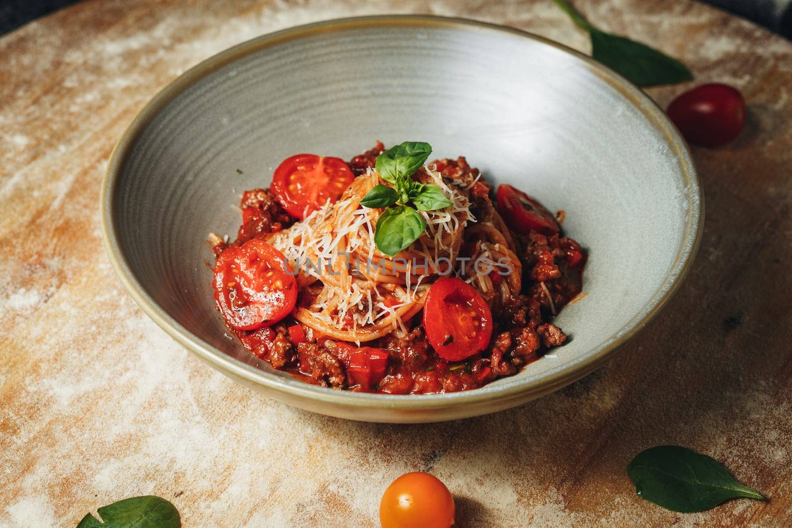 A bowl of spaghetti topped with ripe tomatoes and fresh basil leaves, capturing the essence of Italian cuisine.