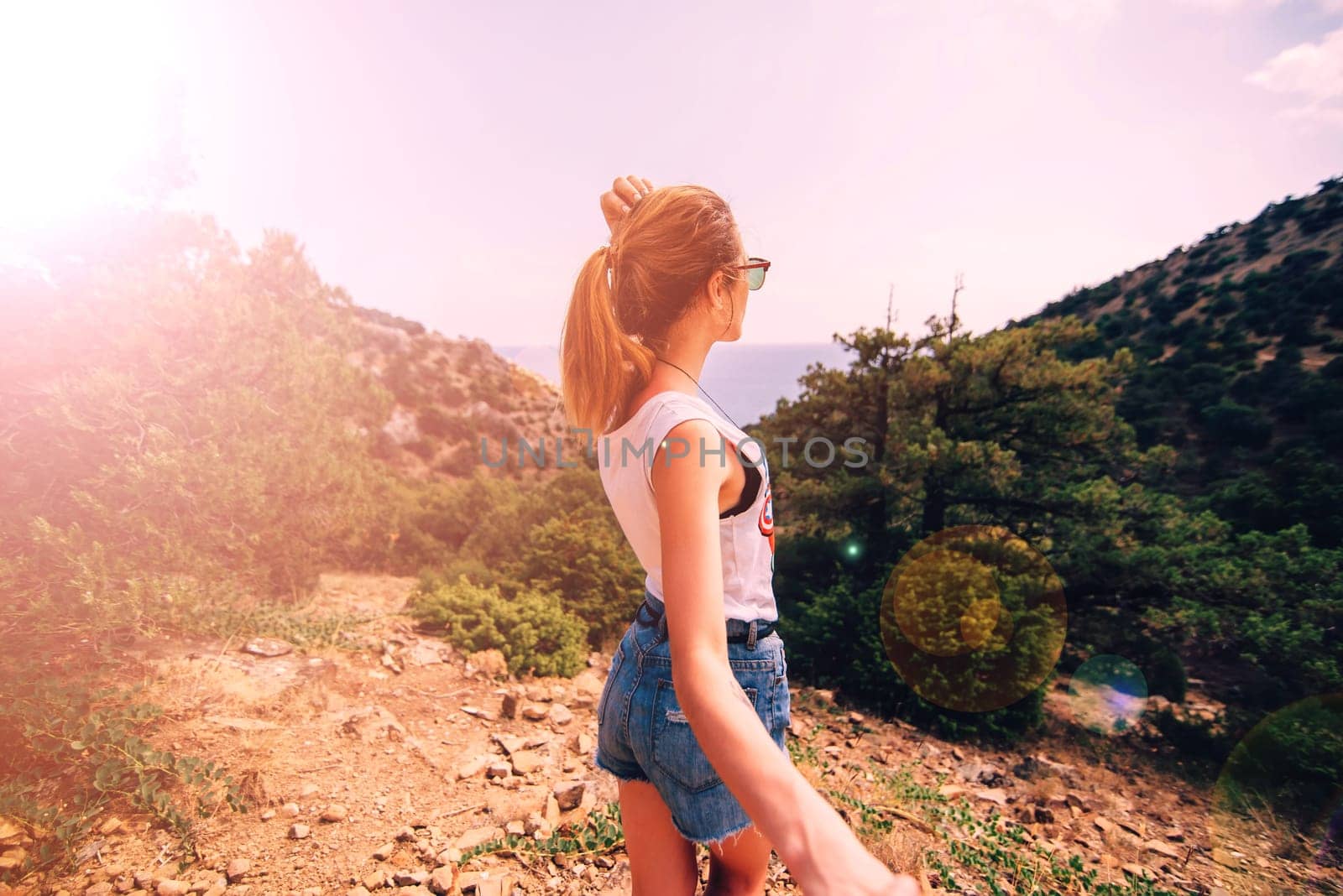 girl holds her boyfriend hand on vacation on a Sunny day in the background of the mountains and the sea. Follow me