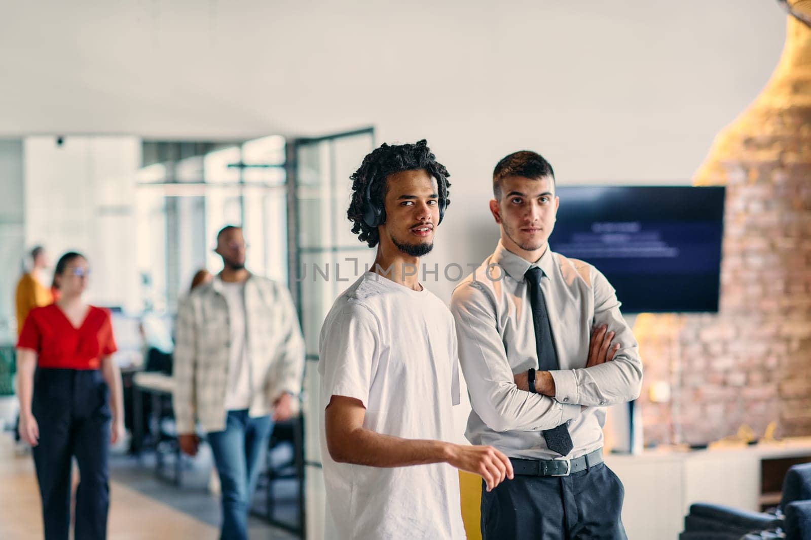 A group of colleagues, including an African American businessman and a young leader in a shirt and tie, pose together in a modern coworking center office, representing a dynamic blend of professionalism and collaboration by dotshock