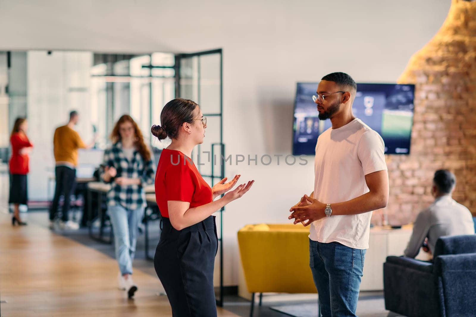 Young business colleagues, including an African American businessman, engage in a conversation about business issues in the hallway of a modern startup coworking center, exemplifying dynamic problem solving and collaboration by dotshock