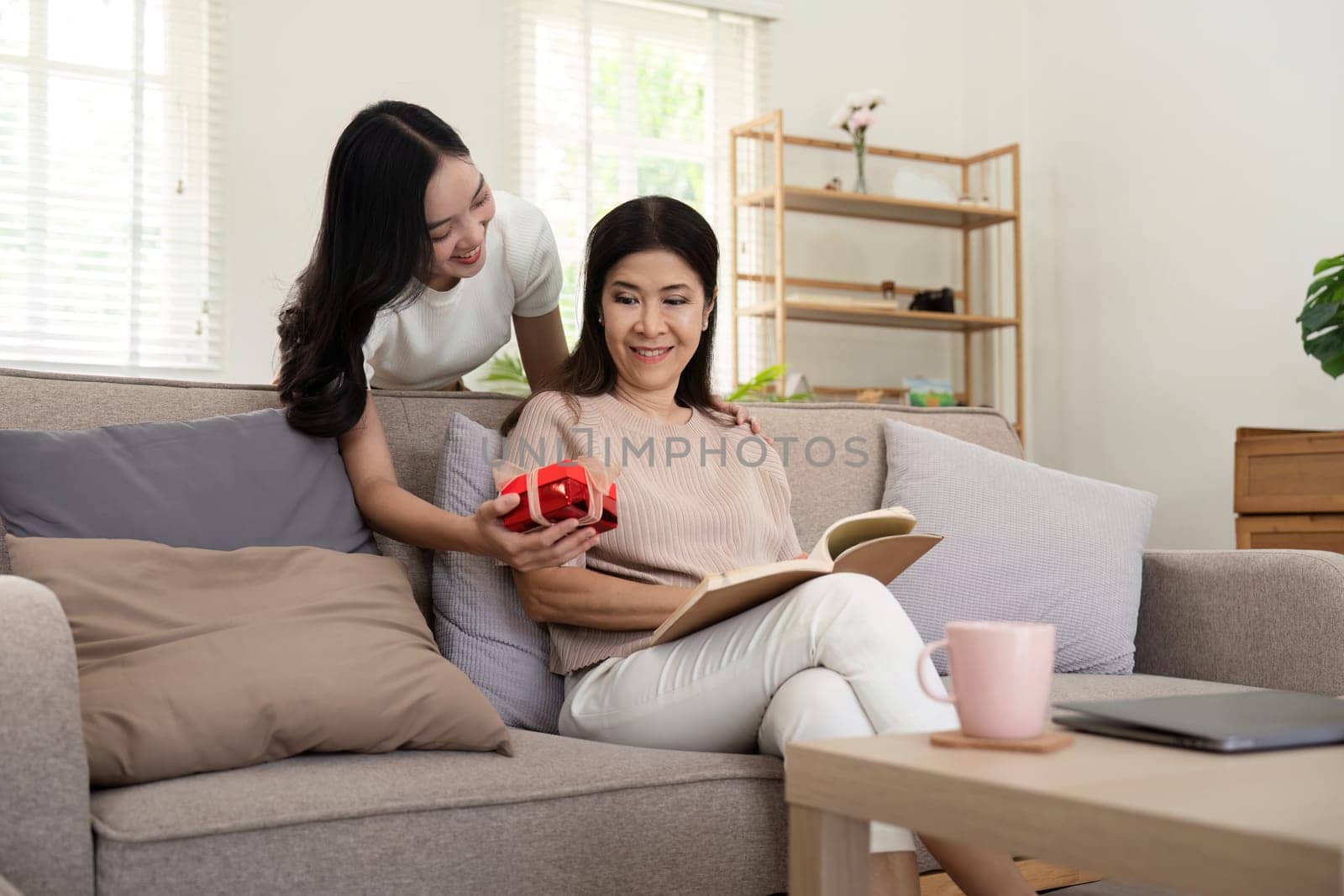 Happy mother's day Beautiful young woman and her mother with gift box at home by nateemee