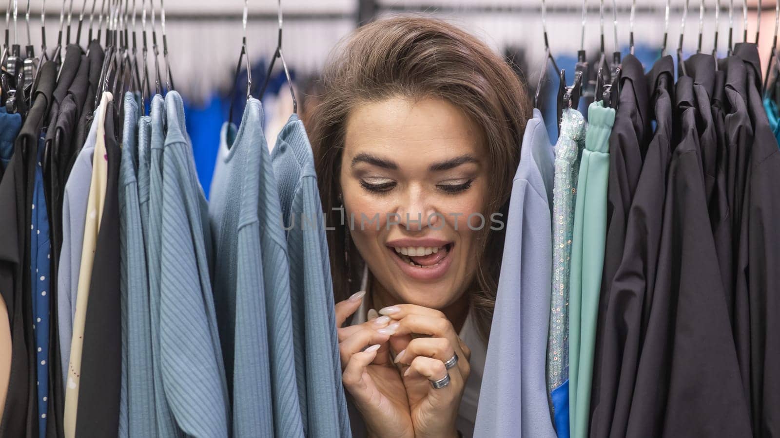 A fat woman in a plus size store peeks out from behind racks of clothes