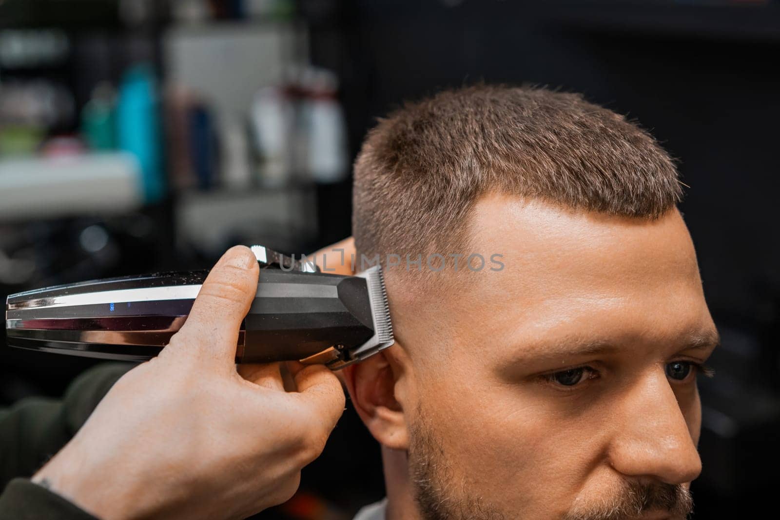 Barber uses trimmer to cut client hair in barbershop by vladimka