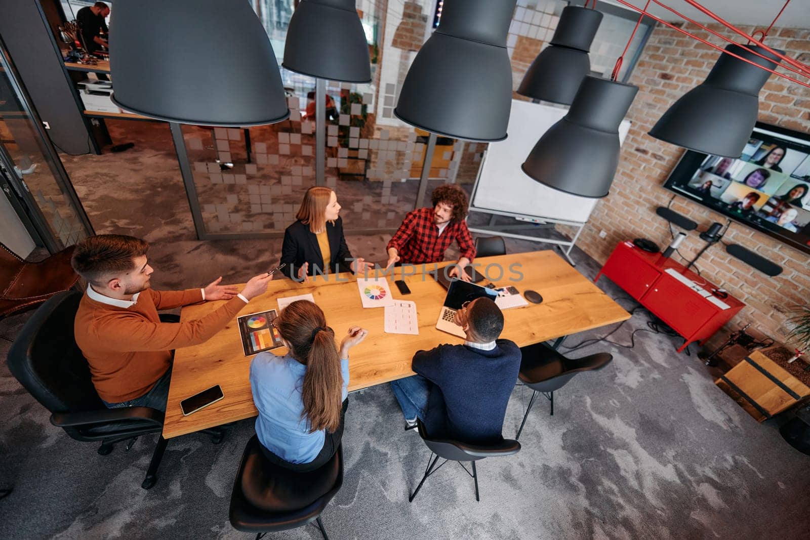 Top view of a modern startup office, a diverse team of business professionals engage in discussions on various projects and develop new business strategies, epitomizing creativity and innovation in the entrepreneurial landscape by dotshock