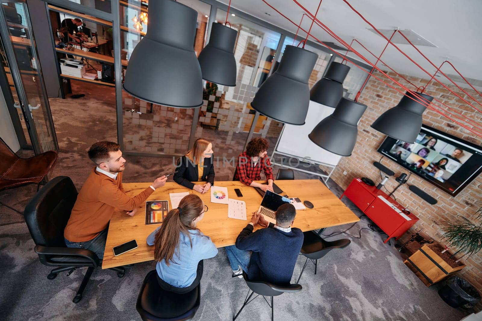 Top view of a modern startup office, a diverse team of business professionals engage in discussions on various projects and develop new business strategies, epitomizing creativity and innovation in the entrepreneurial landscape.