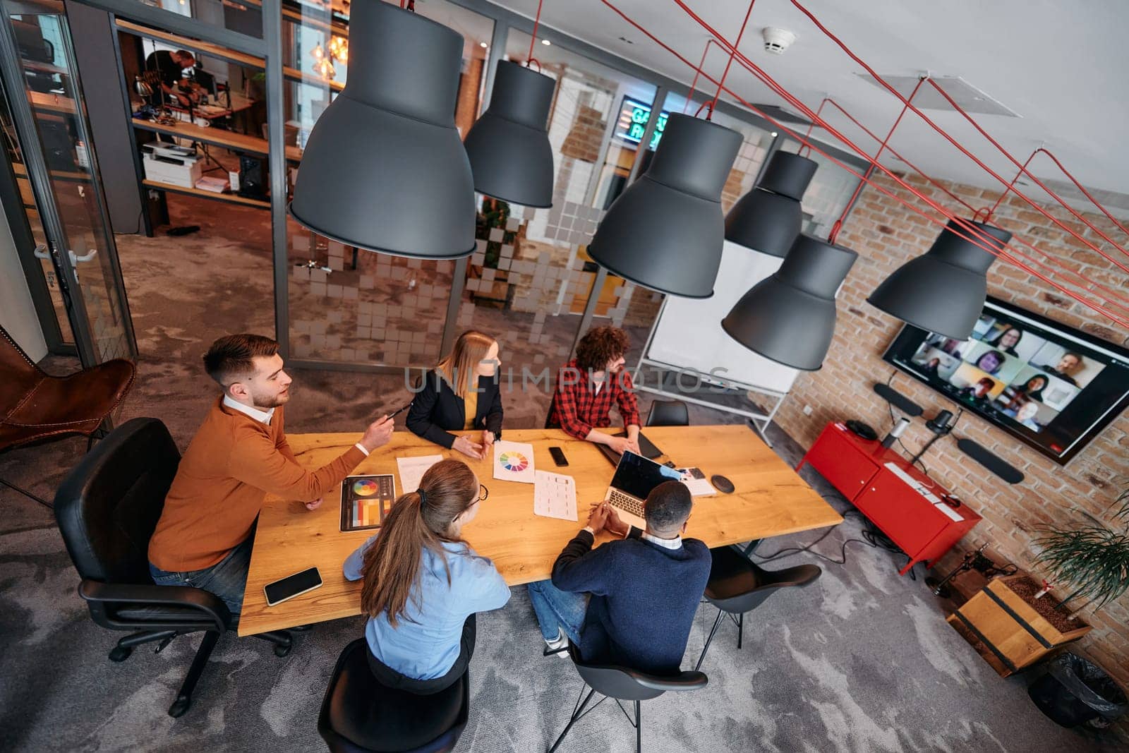 Top view of a modern startup office, a diverse team of business professionals engage in discussions on various projects and develop new business strategies, epitomizing creativity and innovation in the entrepreneurial landscape.