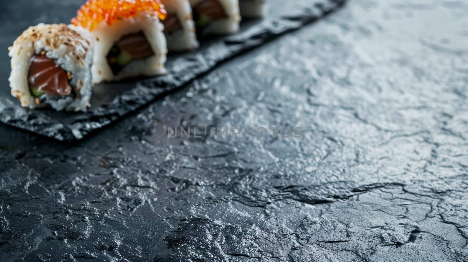 A close-up of sushi rolls artfully presented on a textured dark slate, highlighting the details and colors. Banner with copy space by sfinks