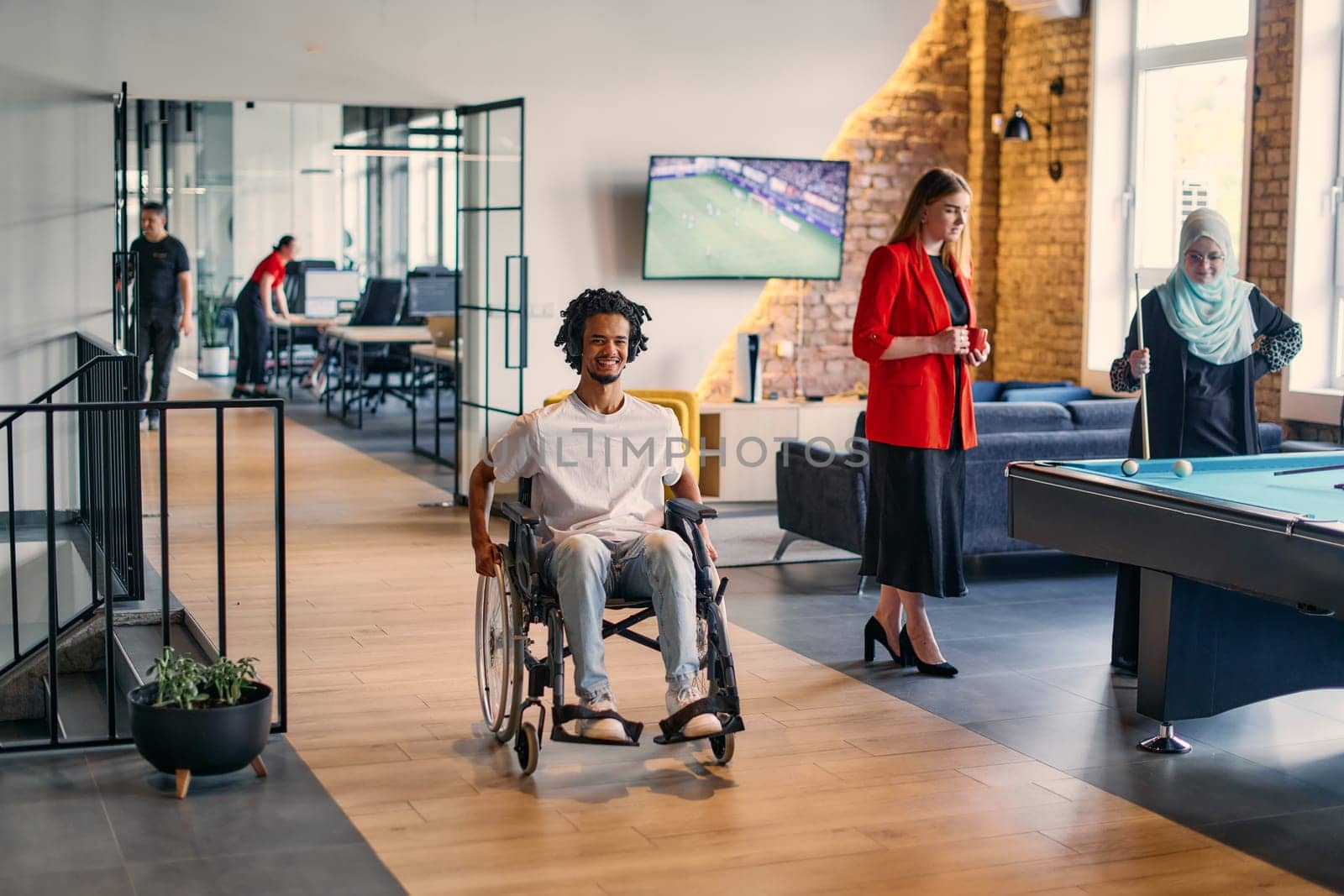 An African-American young entrepreneur in a wheelchair is surrounded by his business colleagues in a modern office setting, embodying diversity and collaboration in the workplace by dotshock