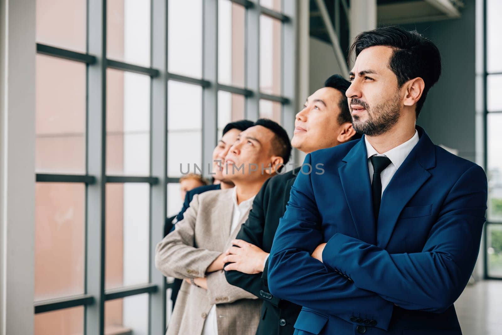 In their office vibrant group portrait showcases young businesspeople and businessman with crossed arms. They exemplify a successful and diverse team, characterized by strong leadership and teamwork.