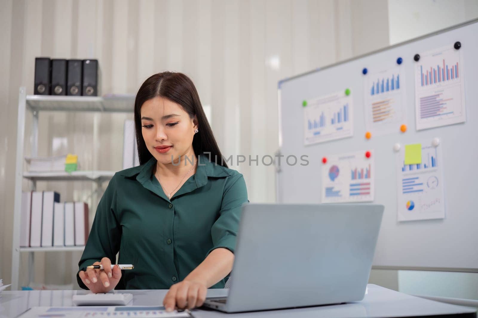 Businesswoman accountant using calculator and laptop for financial data saving in office room, Business financial, tax, accounting concept by nateemee