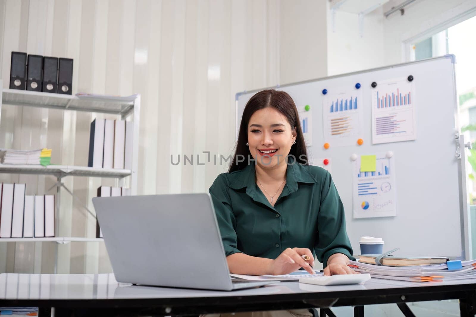 Businesswoman accountant using calculator and laptop for financial data saving in office room, Business financial, tax, accounting concept.