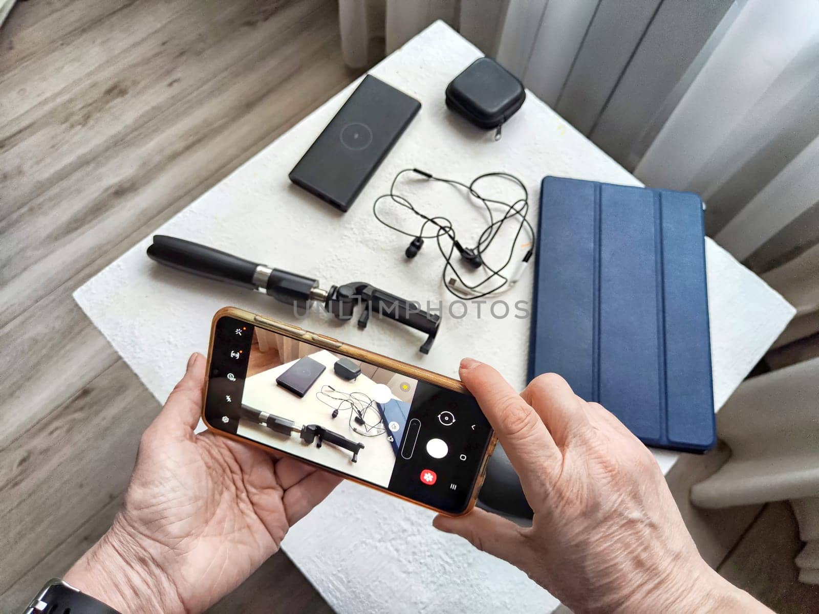 Hands of Senior woman Capturing Tech Gadgets With Smartphone. Elderly blogger take a close-up shot of electronic accessories by keleny