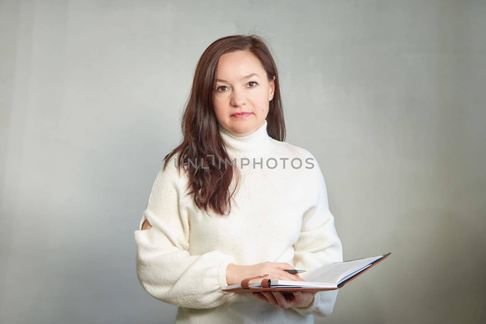 Confident middle aged Business woman in White Turtleneck with Notebook. A professional mature woman ready for a meeting by keleny